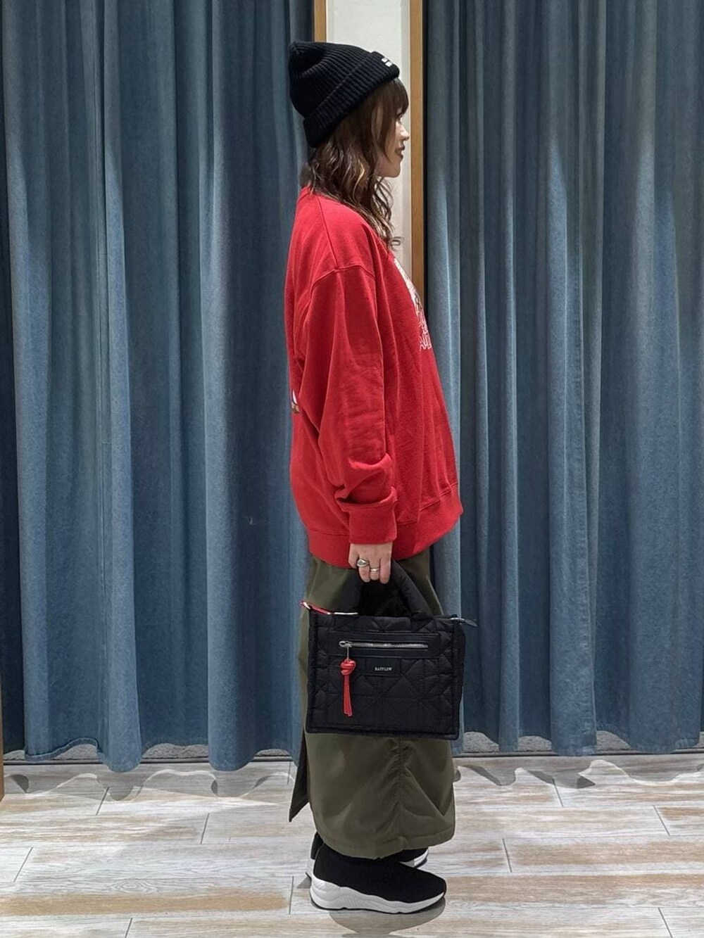 ブラック系のショルダーバッグ、グリーン系のスカート、ブラック系のブーツを着用したレディースの冬コーディネートの2枚目の写真