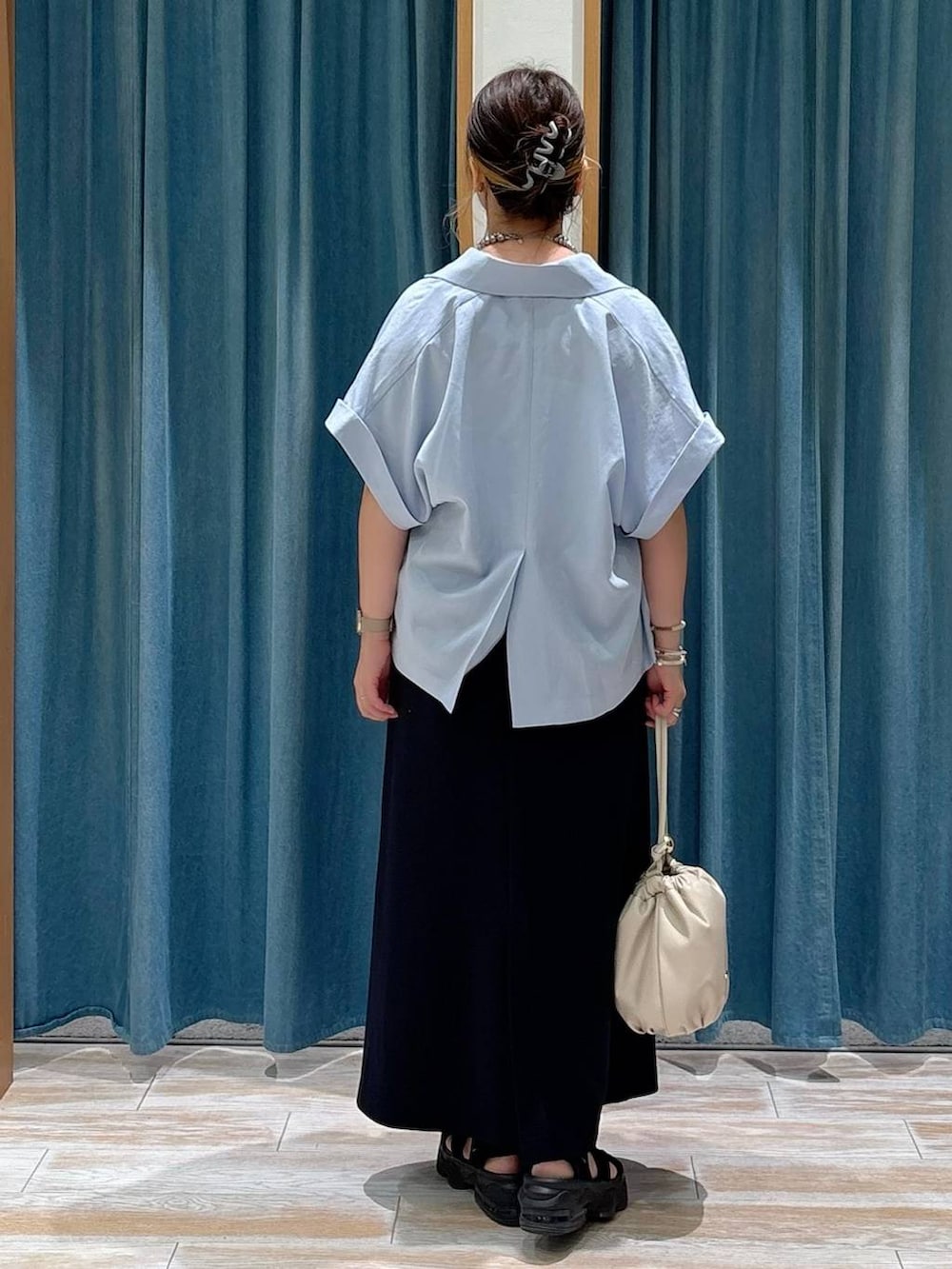 ホワイト系のキャミソール、ホワイト系のショルダーバッグ、ブラック系のスカートを着用したレディースの夏コーディネートの3枚目の写真