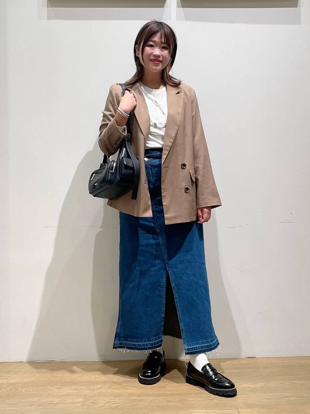 ブルー系のデニムスカート、ブラック系のローファー、ホワイト系のTシャツ/カットソーを着用したレディースの秋コーディネートの2枚目の写真