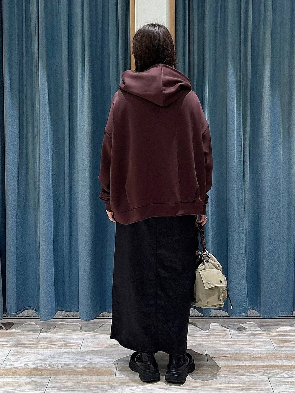 ブラック系のブーツ、ベージュ系のハンドバッグ、ブラック系のスカートを着用したレディースの冬コーディネートの3枚目の写真