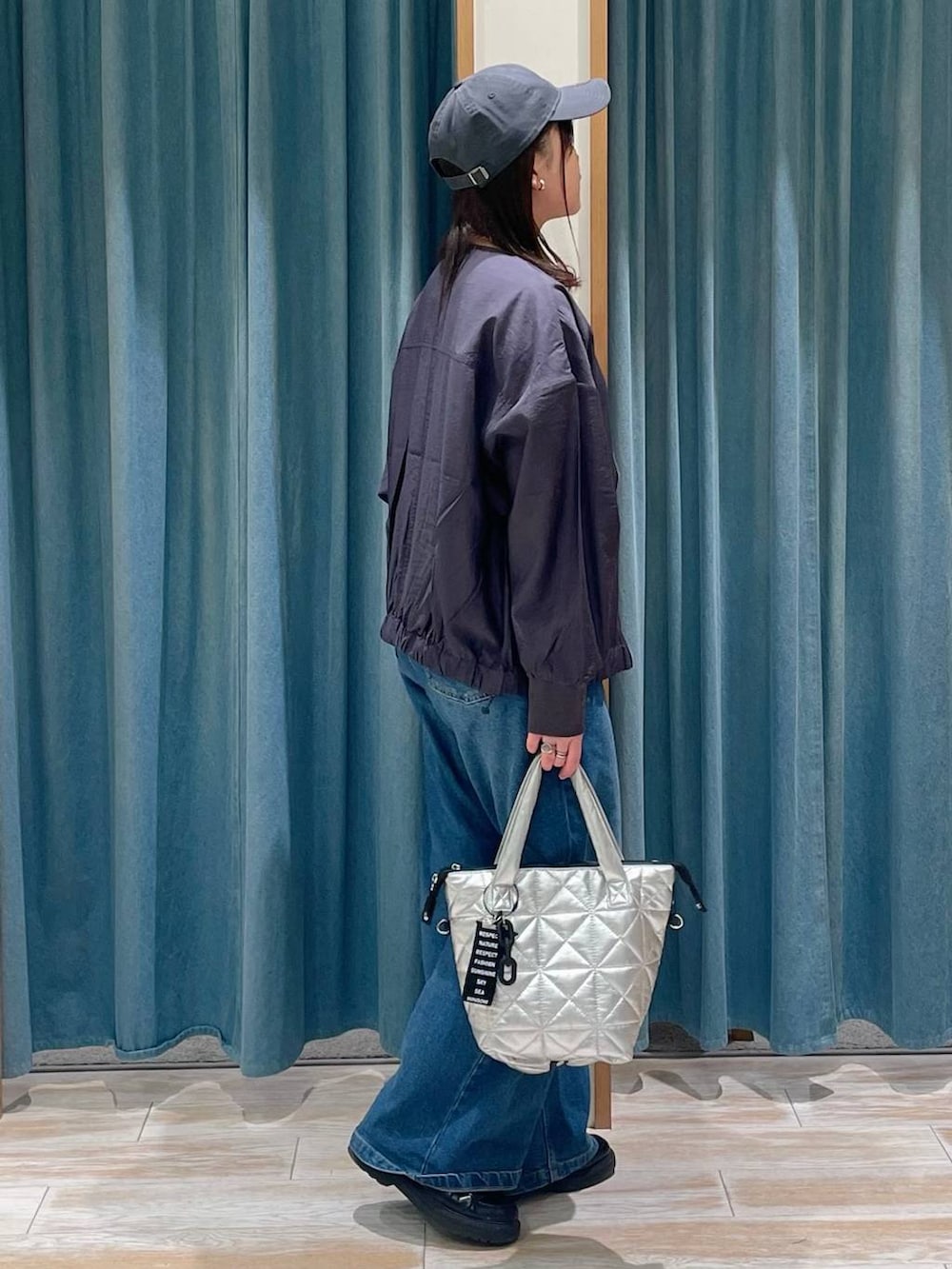 ブルー系のデニムパンツ、グレー系のブルゾン、シルバー系のトートバッグを着用したレディースの春コーディネートの2枚目の写真