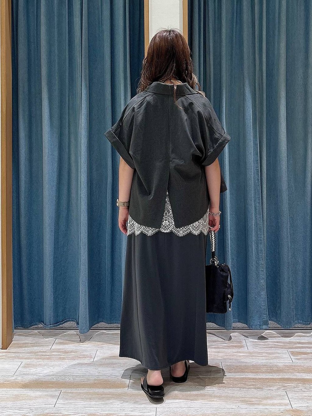 ブラック系のショルダーバッグ、ブラック系のサンダル、グレー系のスカートを着用したレディースの夏コーディネートの3枚目の写真