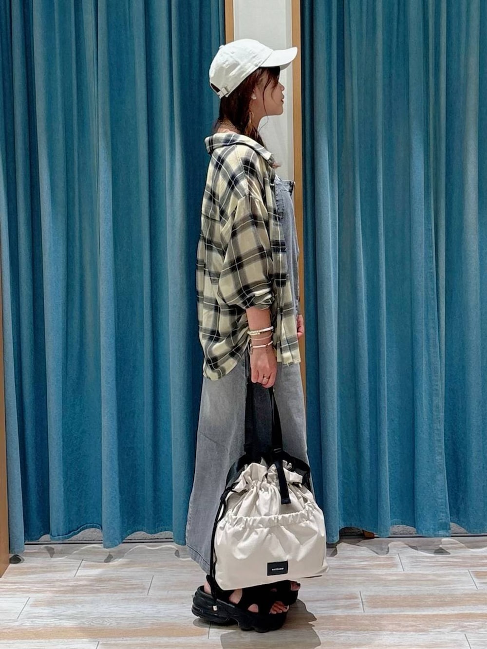 ホワイト系のキャミソール、ホワイト系のトートバッグ、ブラック系のジャンパースカートを着用したレディースの夏コーディネートの2枚目の写真