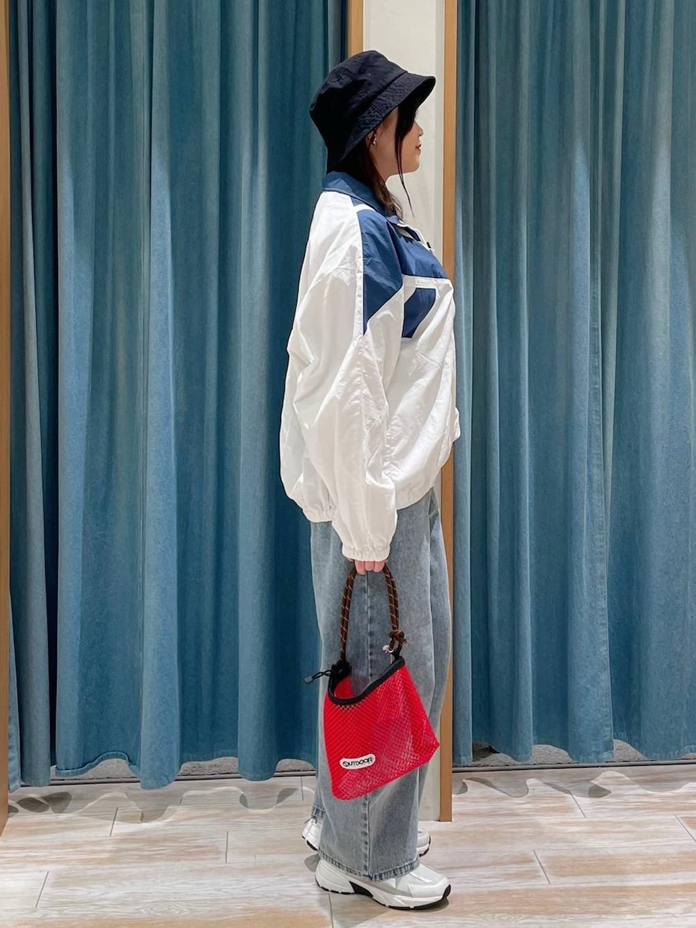 レッド系のショルダーバッグ、ホワイト系のナイロンジャケット、ブルー系のデニムパンツを着用したレディースの冬コーディネートの2枚目の写真