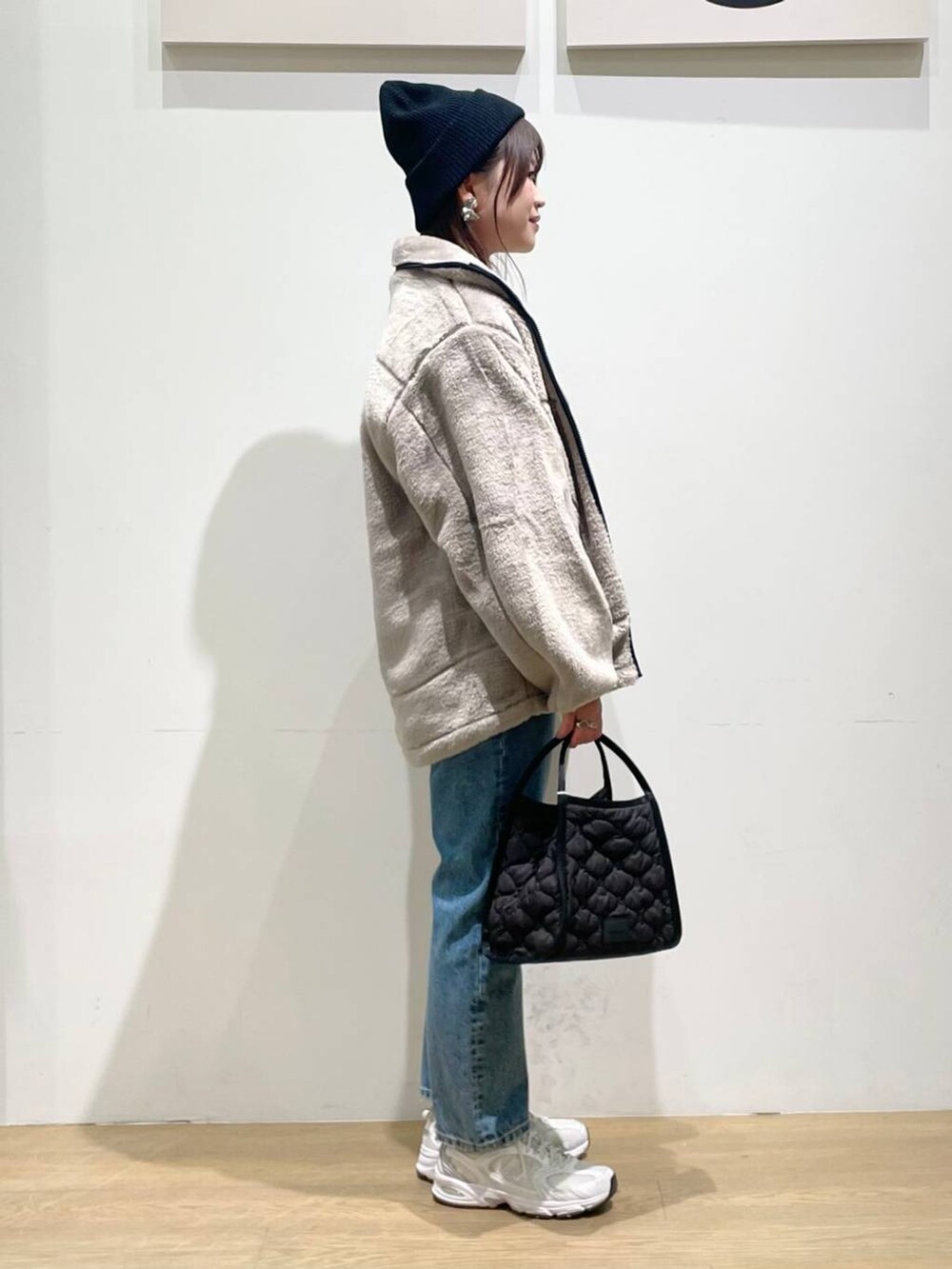 ベージュ系のブルゾン、ブラック系のハンドバッグ、ブルー系のデニムパンツを着用したレディースの秋コーディネートの2枚目の写真