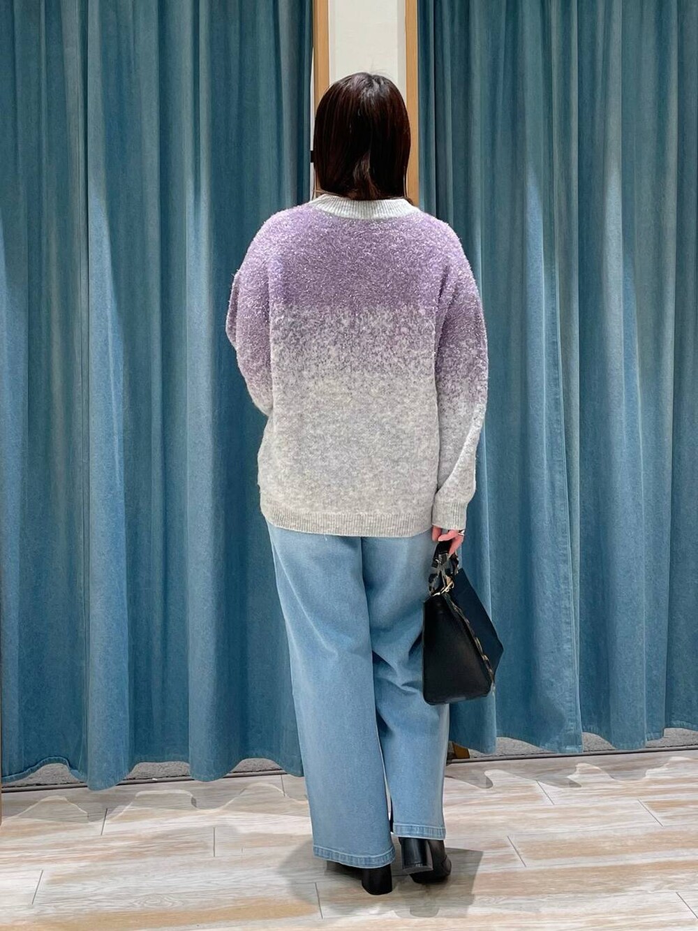 ブラック系のブーツ、ブラック系のハンドバッグ、ブルー系のデニムパンツを着用したレディースの冬コーディネートの3枚目の写真