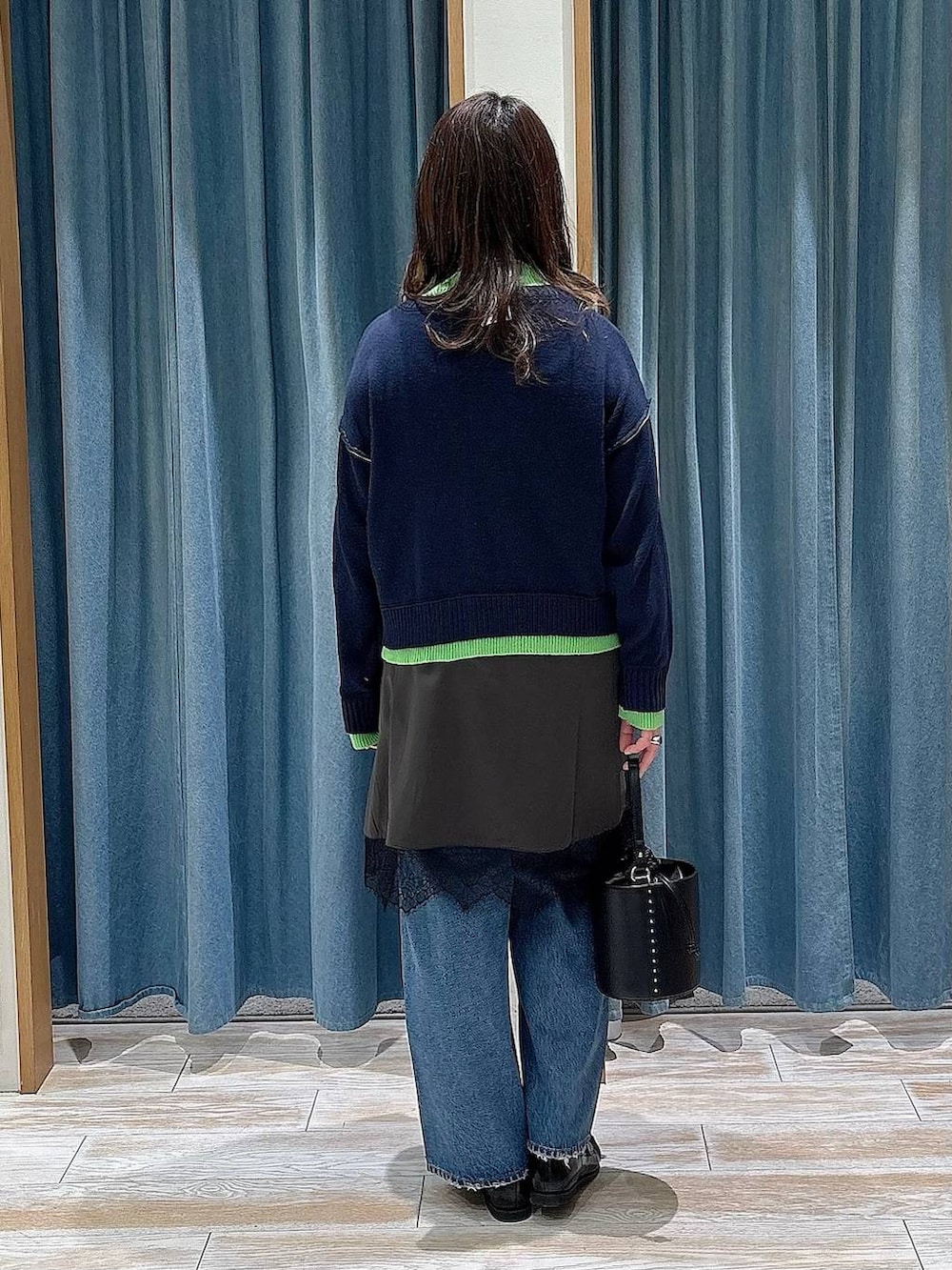 ブラック系のハンドバッグ、ブルー系のデニムパンツ、ブラック系のローファーを着用したレディースの冬コーディネートの2枚目の写真