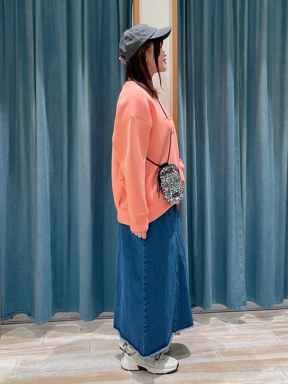 グレー系のショルダーバッグ、ピンク系のTシャツ/カットソー、ブルー系のデニムスカートを着用したレディースの冬コーディネートの2枚目の写真