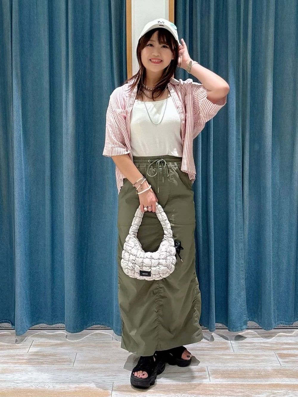 ホワイト系のキャミソール、グリーン系のスカート、レッド系のシャツ/ブラウスを着用したレディースの夏コーディネートの4枚目の写真