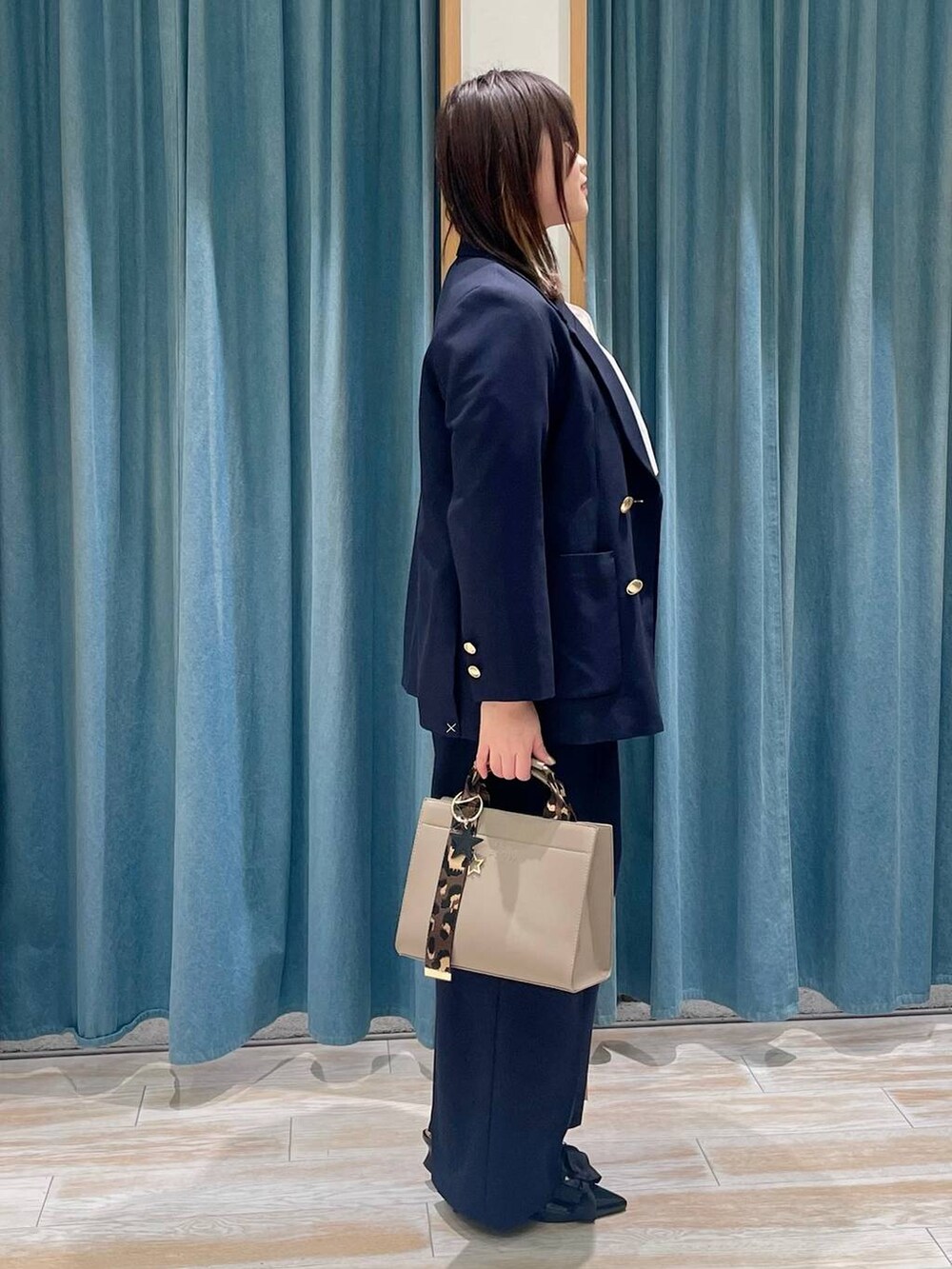 ベージュ系のハンドバッグ、ブルー系のテーラードジャケット、ブルー系のその他パンツを着用したレディースの冬コーディネートの2枚目の写真