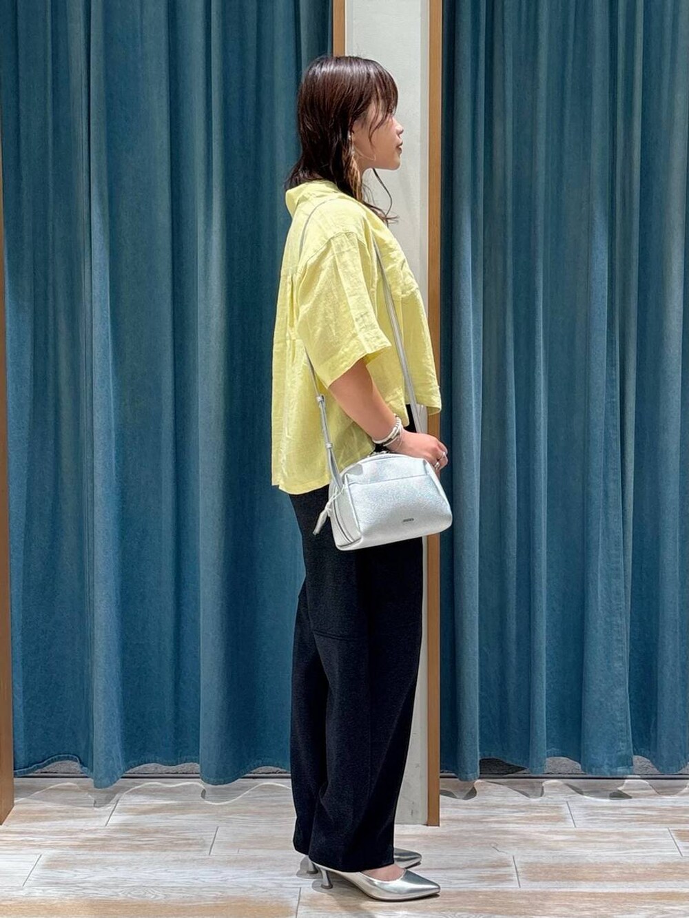 シルバー系のパンプス、ホワイト系のキャミソール、シルバー系のショルダーバッグを着用したレディースの夏コーディネートの2枚目の写真