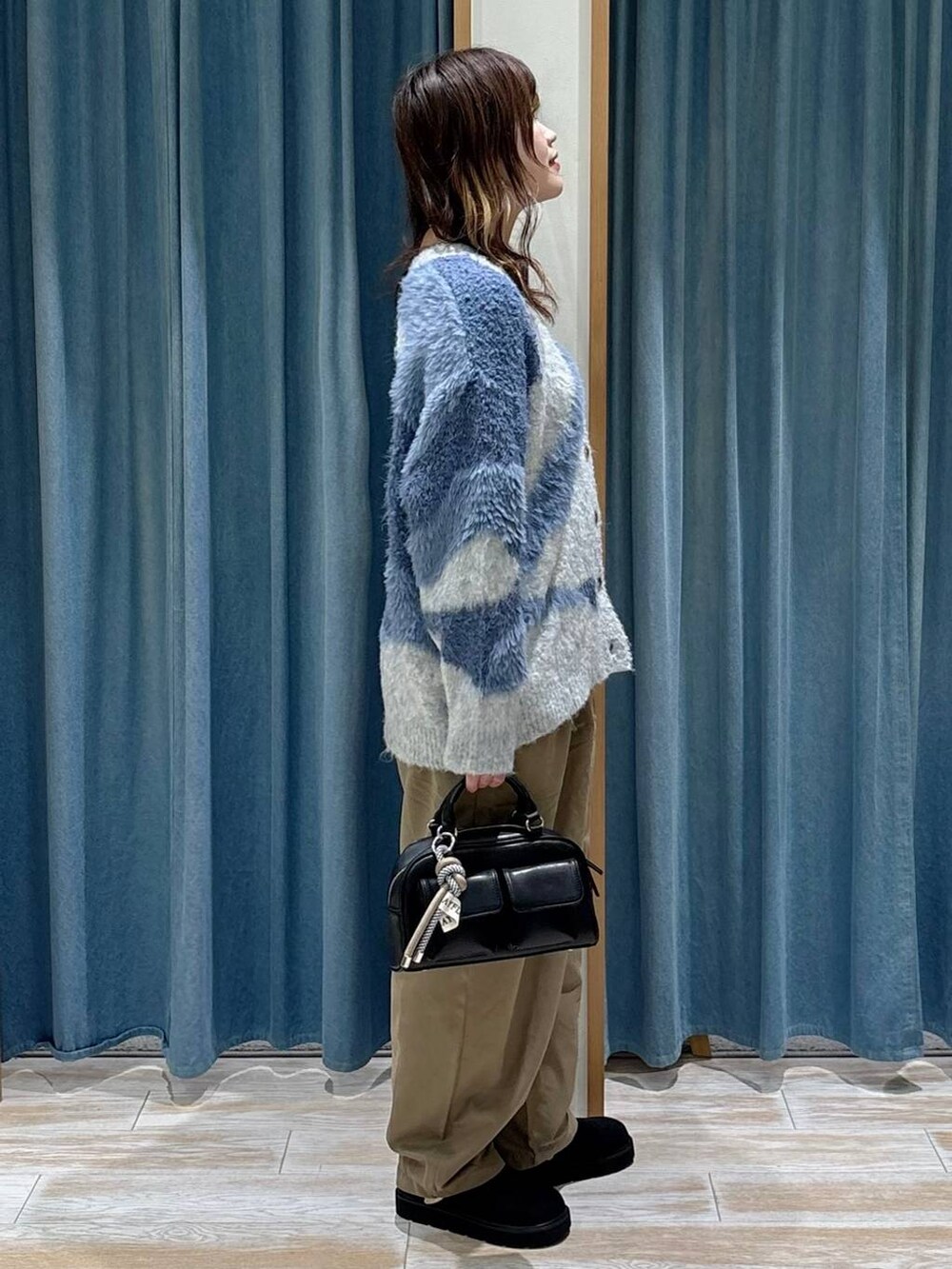 ブラック系のボストンバッグ、ブラック系のブーツ、ブルー系のカーディガン/ボレロを着用したレディースの秋コーディネートの2枚目の写真