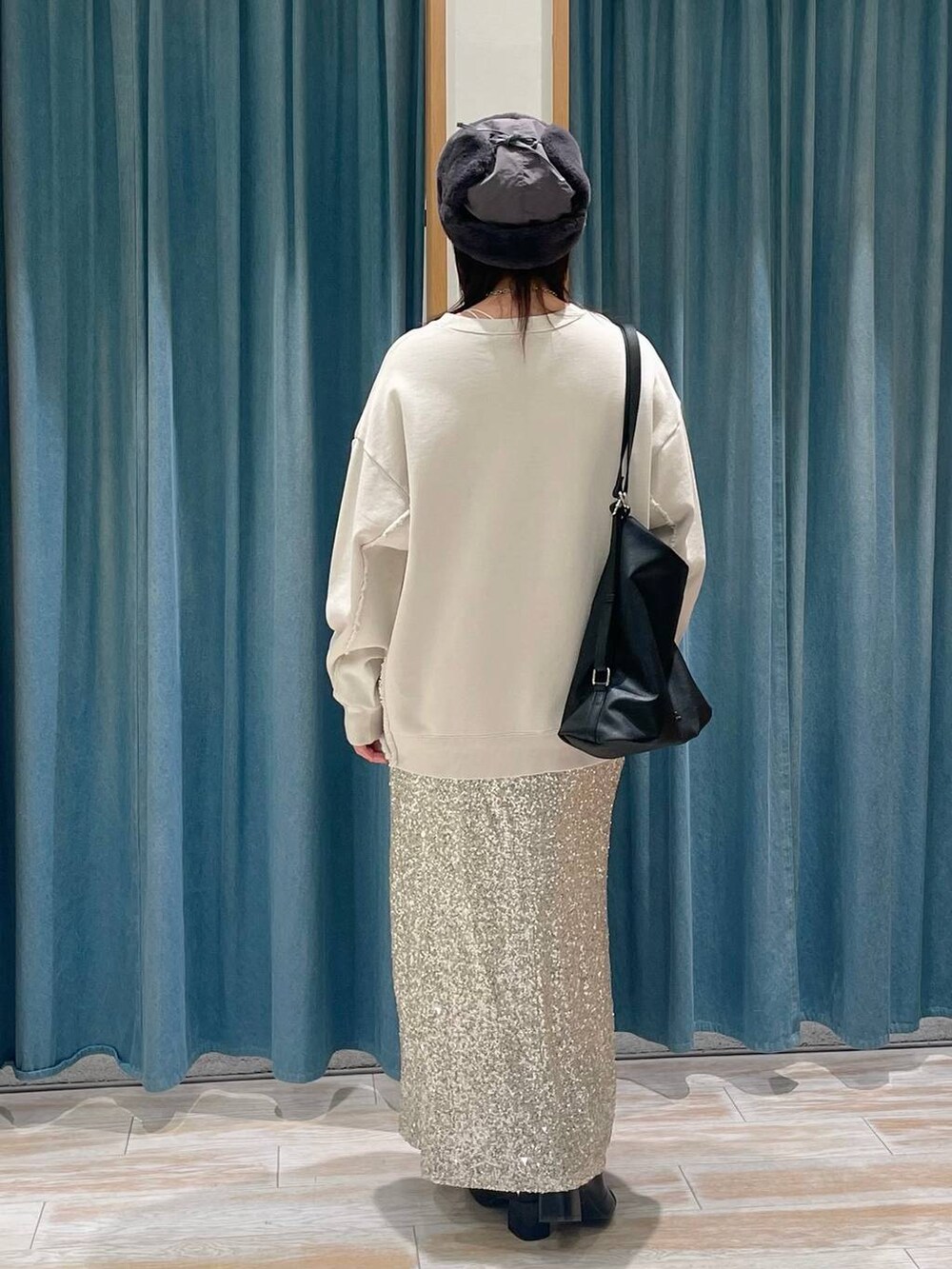 ブラック系のブーツ、ブラック系のショルダーバッグ、ベージュ系のスカートを着用したレディースの冬コーディネートの3枚目の写真