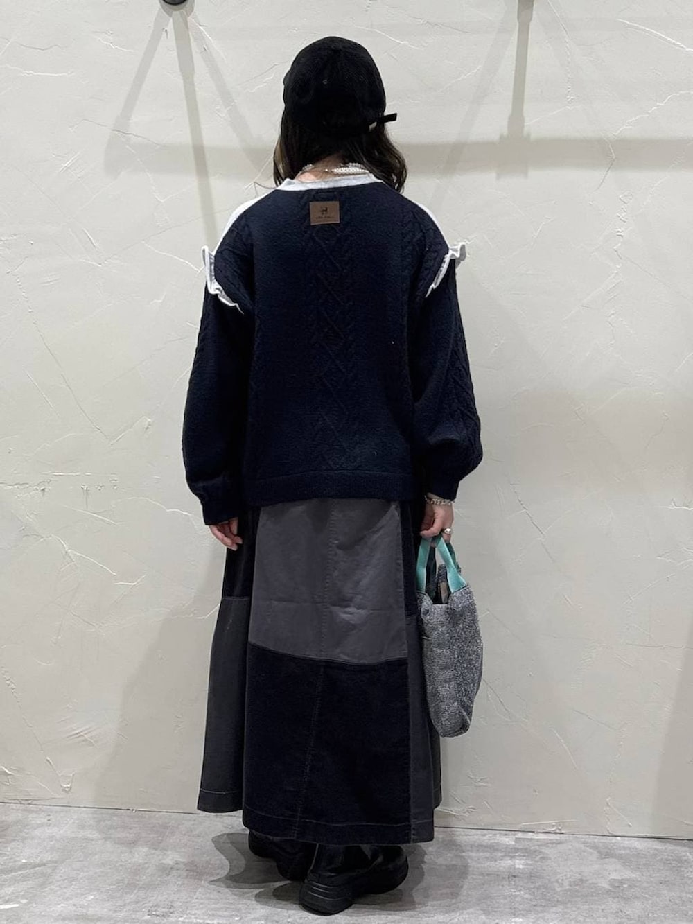 グレー系のスカート、シルバー系のトートバッグ、グレー系のニット/セーターを着用したレディースの冬コーディネートの3枚目の写真