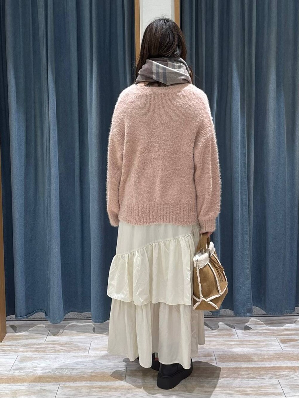 ブラック系のブーツ、イエロー系のショルダーバッグ、ベージュ系のスカートを着用したレディースの冬コーディネートの3枚目の写真