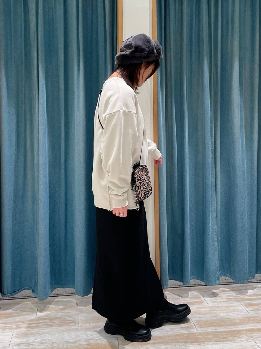 ブラック系のブーツ、ブラウン系のショルダーバッグ、ブラック系のスカートを着用したレディースの冬コーディネートの2枚目の写真