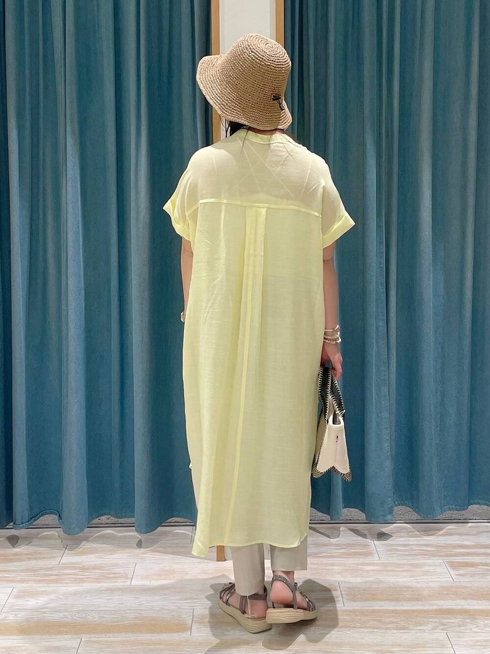 ホワイト系のキャミソール、ベージュ系のトートバッグ、ブラック系のサンダルを着用したレディースの春コーディネートの3枚目の写真