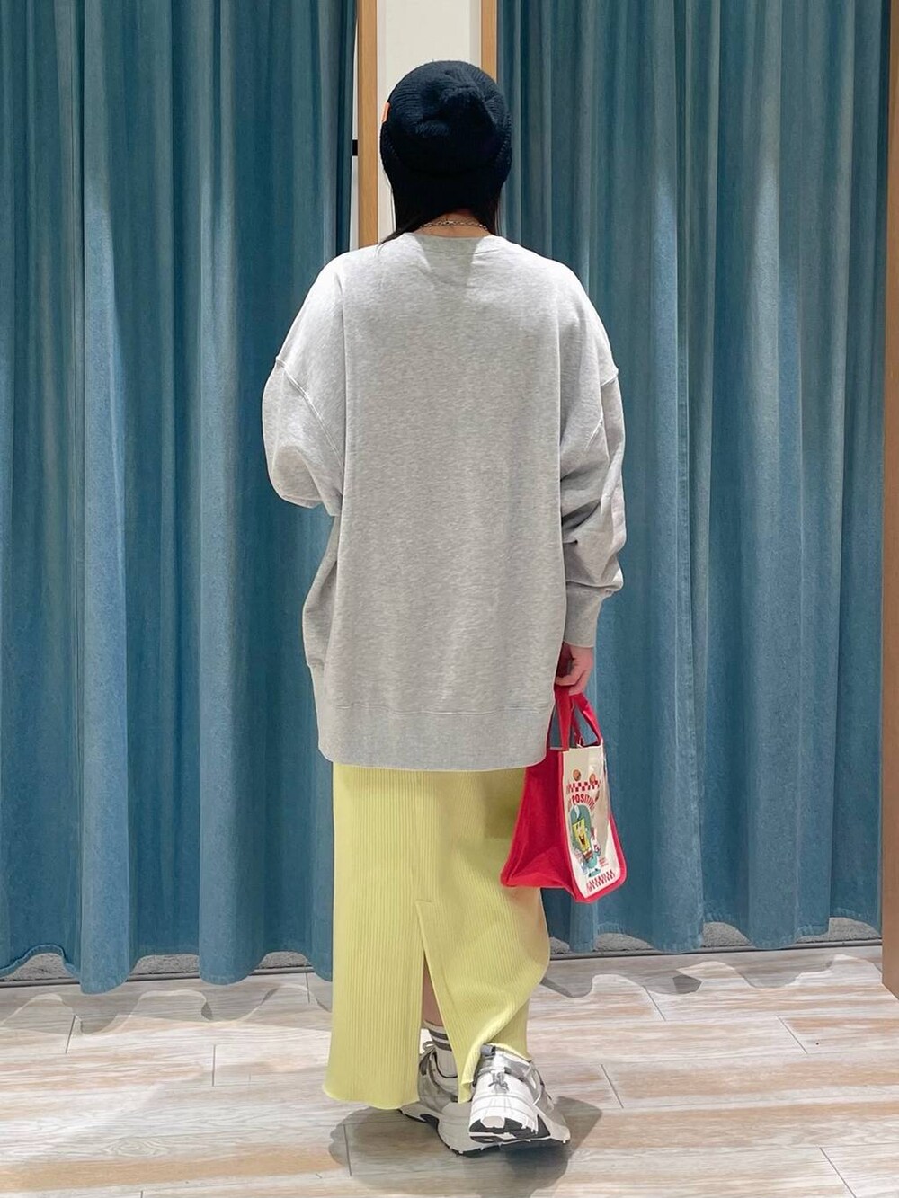 レッド系のトートバッグ、イエロー系のスカート、グレー系のスウェットを着用したレディースの冬コーディネートの3枚目の写真