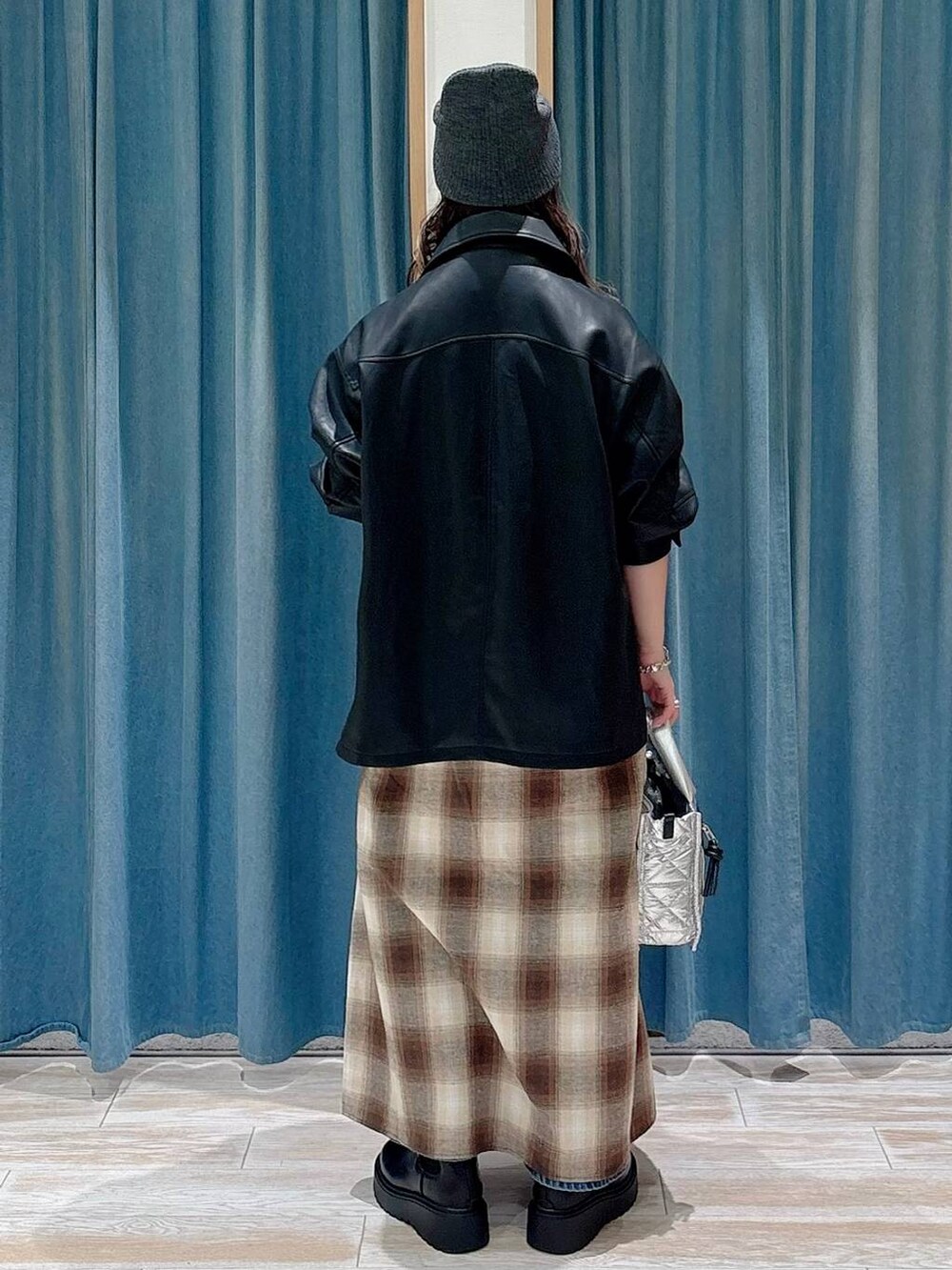 シルバー系のショルダーバッグ、ブラック系のブーツ、ブルー系のデニムパンツを着用したレディースの秋コーディネートの3枚目の写真