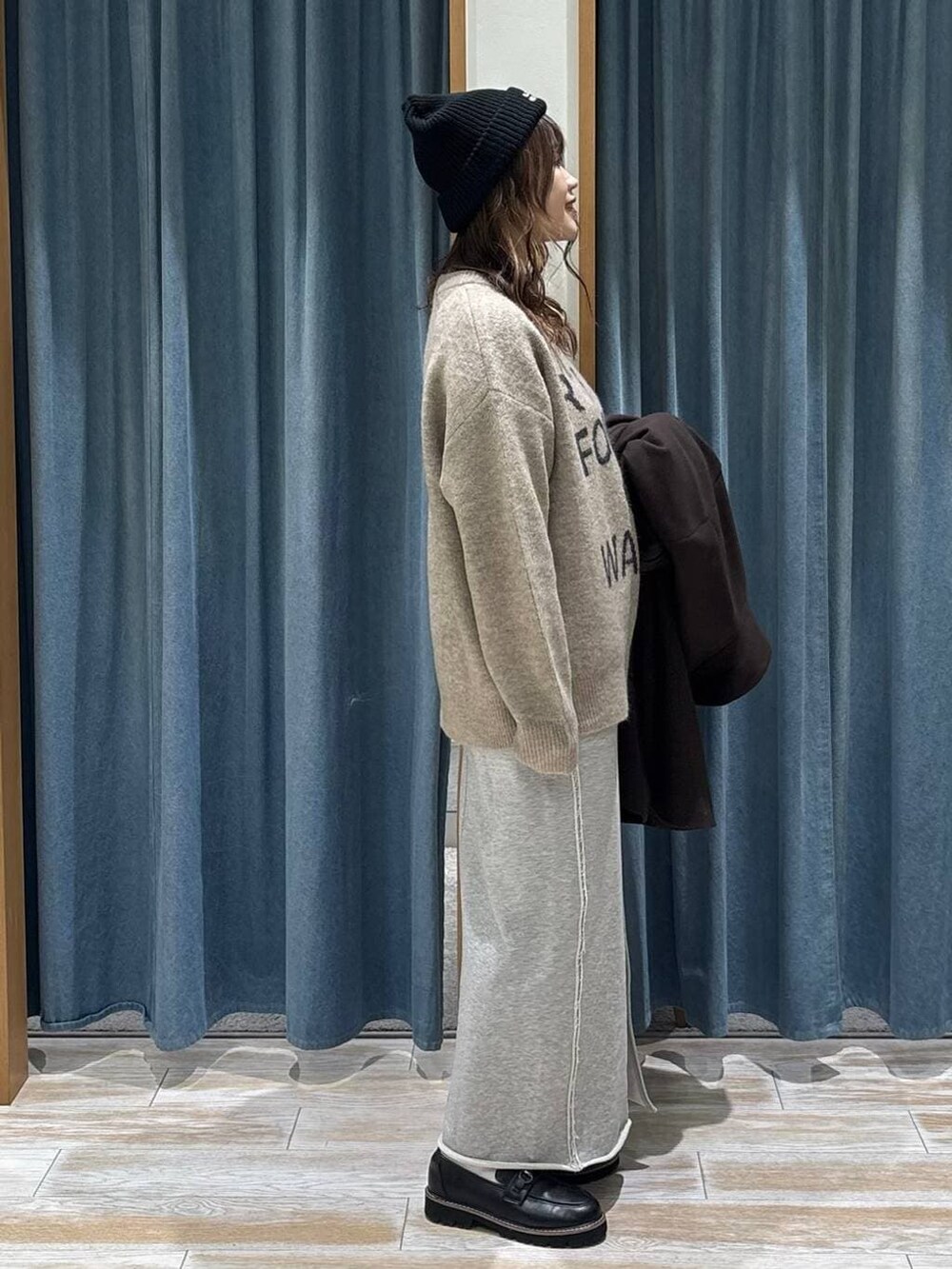 ブラウン系のチェスターコート、ブラック系のローファー、ブラウン系のニット/セーターを着用したレディースの冬コーディネートの2枚目の写真