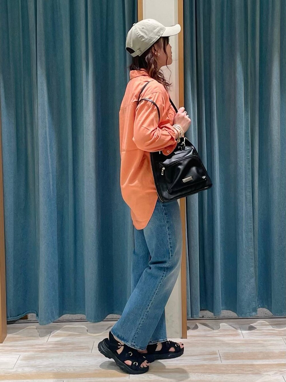 オレンジ系のシャツ/ブラウス、ブルー系のデニムパンツ、ブラック系のサンダルを着用したレディースの春コーディネートの2枚目の写真