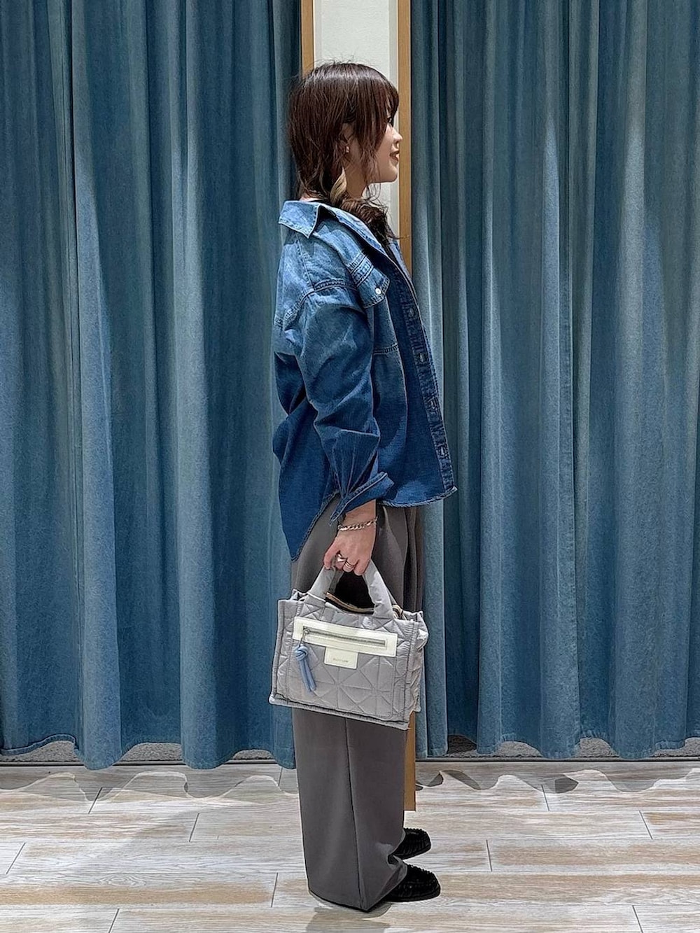 グレー系のショルダーバッグ、ブラック系のローファー、ブルー系のシャツ/ブラウスを着用したレディースの冬コーディネートの2枚目の写真