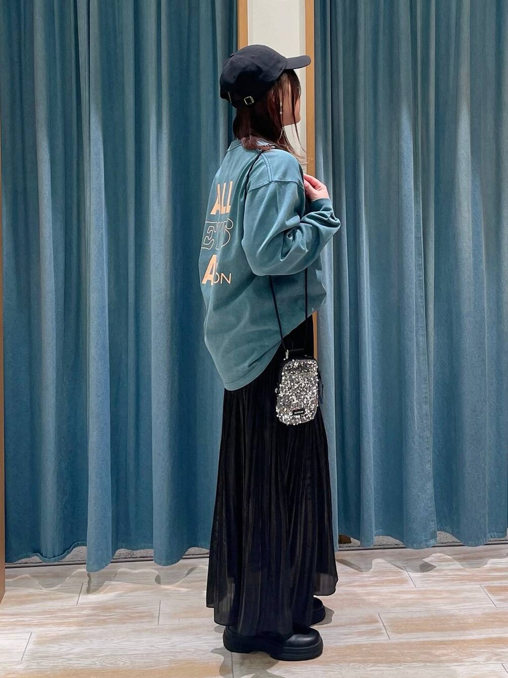 グレー系のショルダーバッグ、ブラック系のブーツ、ブラック系のスカートを着用したレディースの冬コーディネートの2枚目の写真