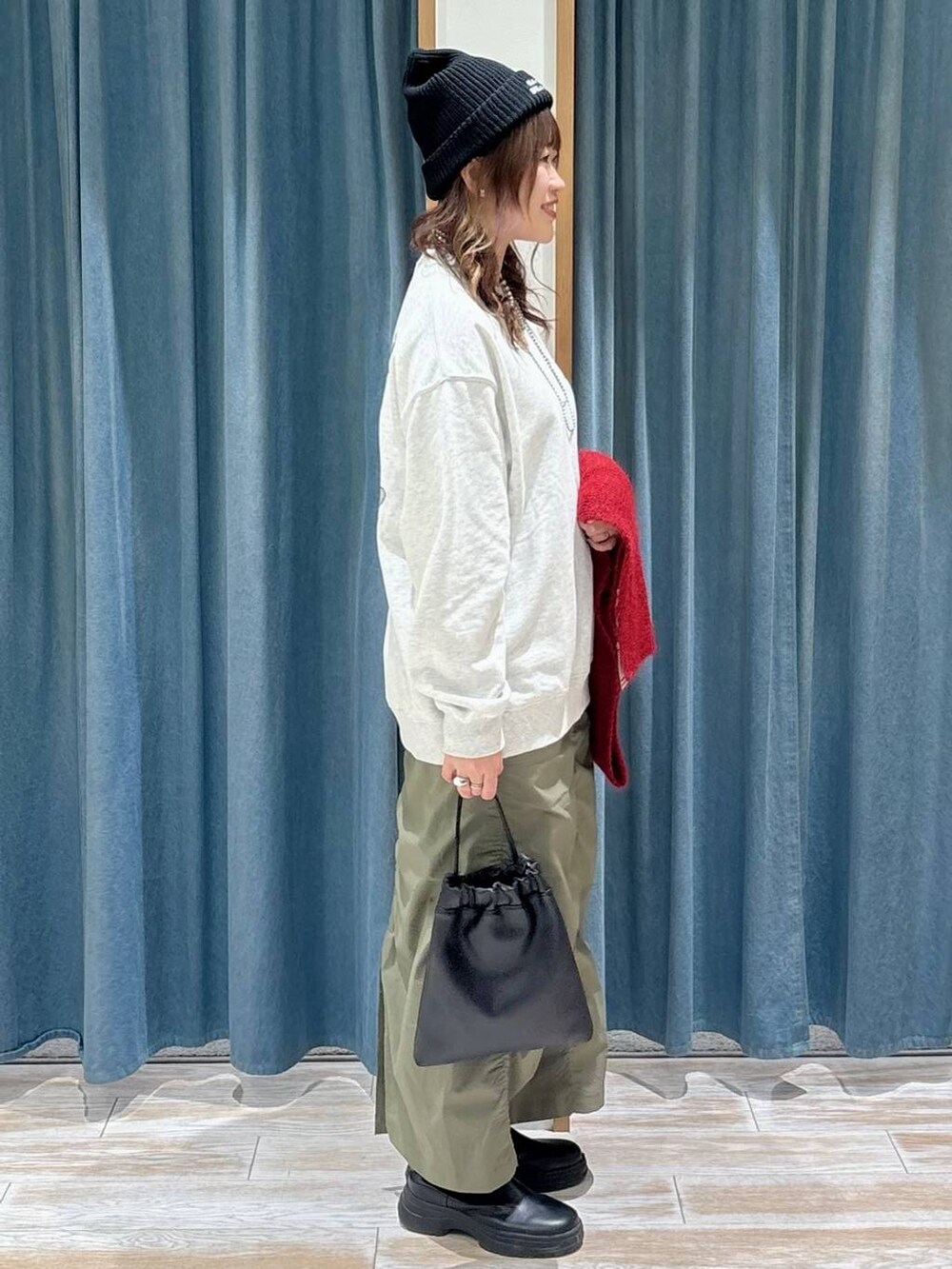 ブラック系のブーツ、グリーン系のスカート、ブラック系のハンドバッグを着用したレディースの秋コーディネートの3枚目の写真