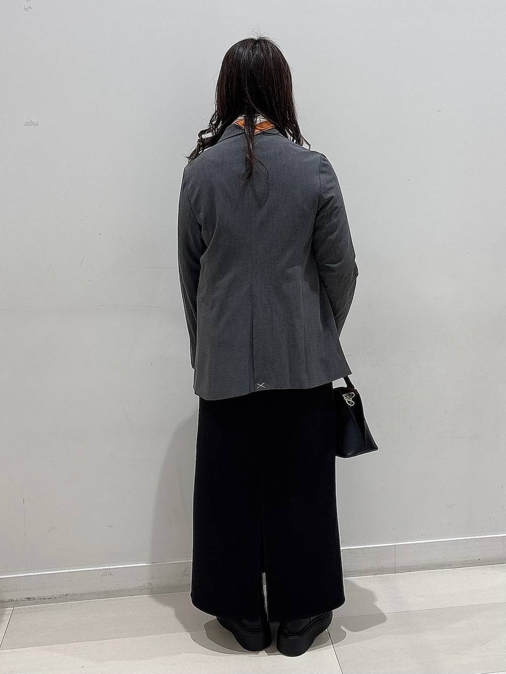 ブラック系のショルダーバッグ、ブラック系のブーツ、グレー系のテーラードジャケットを着用したレディースの冬コーディネートの3枚目の写真