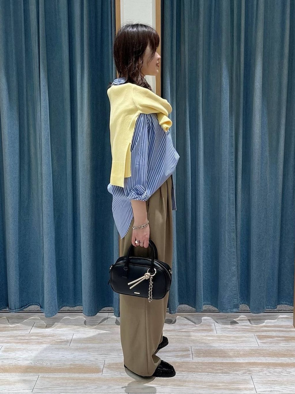 ブラック系のローファー、ブラック系のハンドバッグ、イエロー系のニット/セーターを着用したレディースの春コーディネートの2枚目の写真