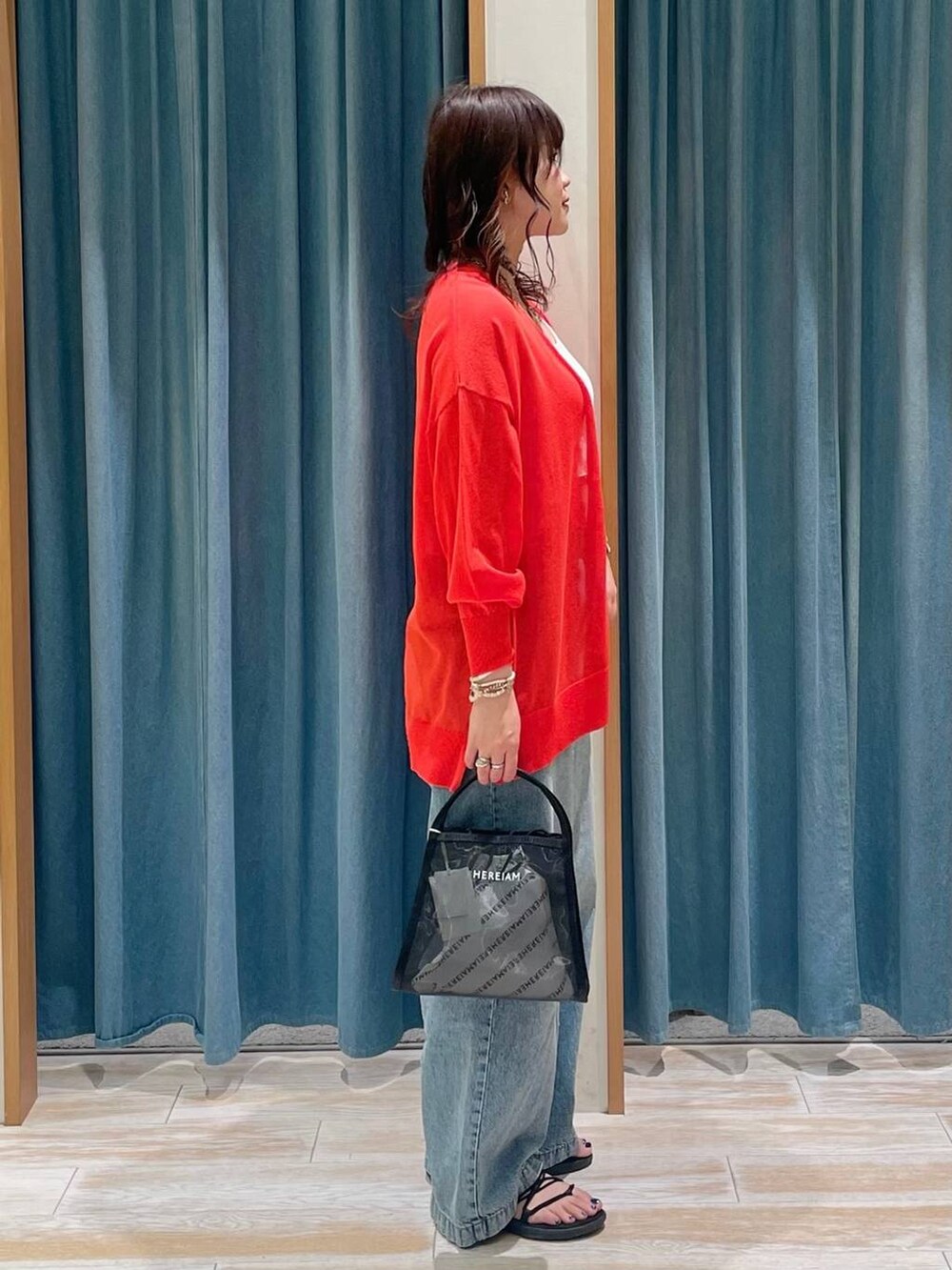 ホワイト系のキャミソール、ブルー系のデニムパンツ、ブラック系のハンドバッグを着用したレディースの春コーディネートの2枚目の写真