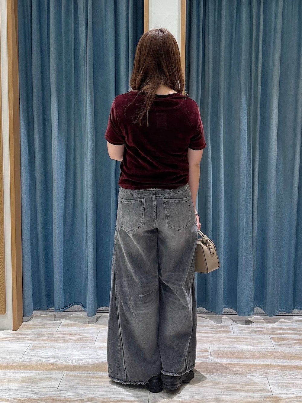 レッド系のTシャツ/カットソー、ベージュ系のハンドバッグ、ブラック系のベルトを着用したレディースの夏コーディネートの3枚目の写真