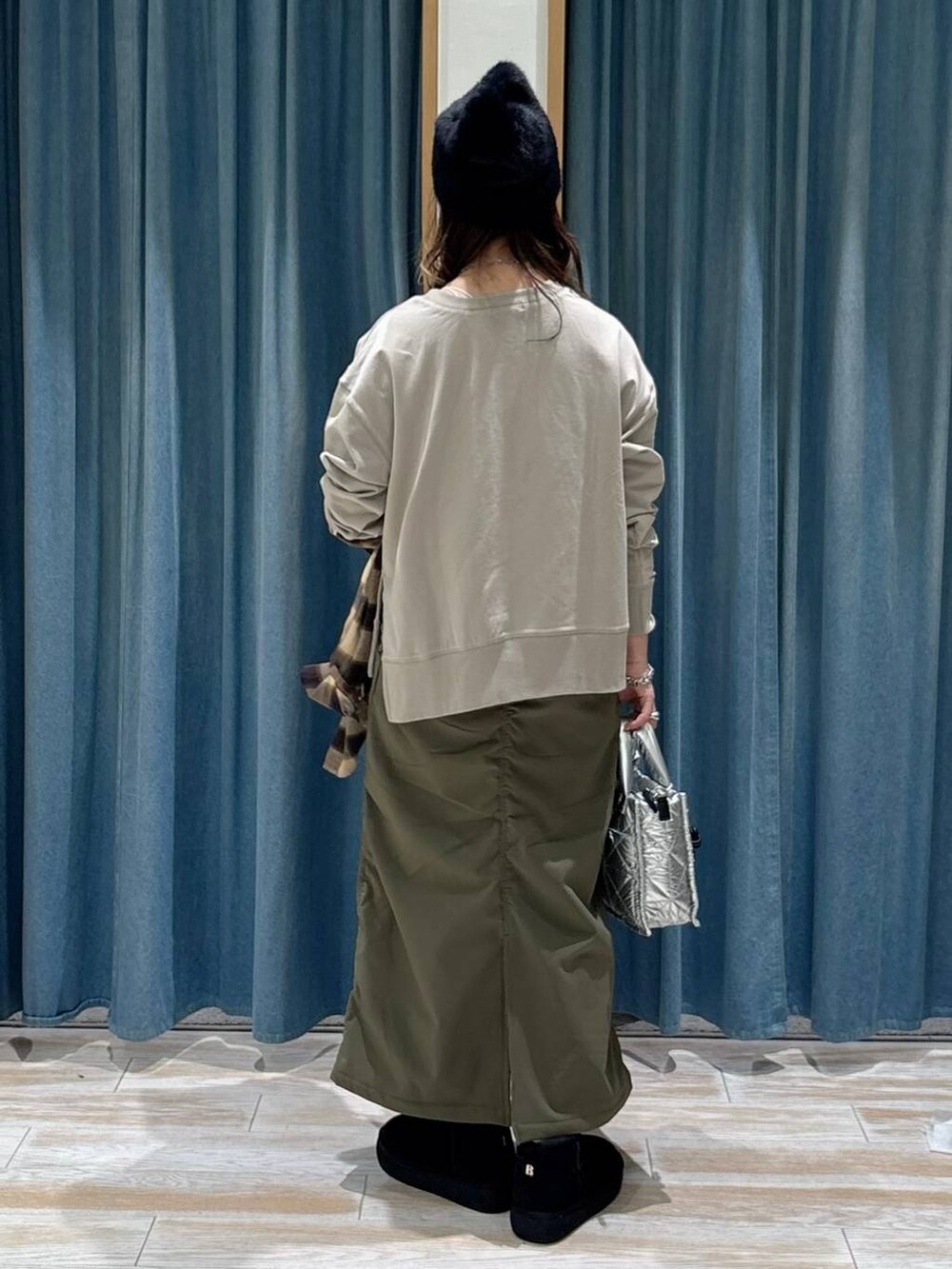 シルバー系のショルダーバッグ、グリーン系のスカート、ブラック系のブーツを着用したレディースの秋コーディネートの3枚目の写真