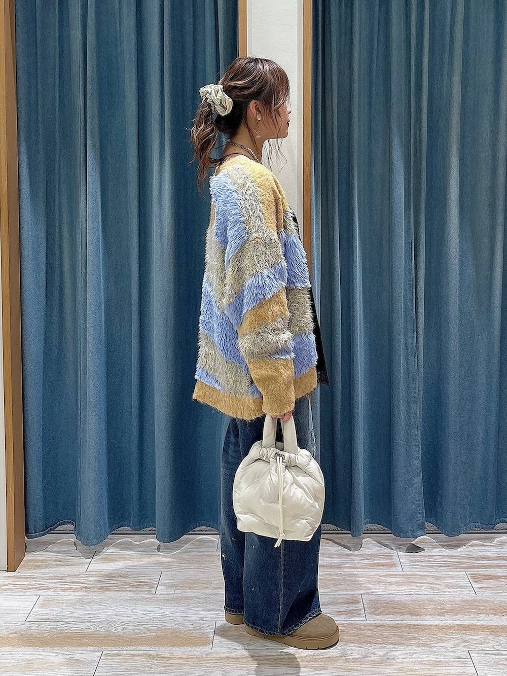 イエロー系のカーディガン/ボレロ、ブルー系のデニムパンツ、ホワイト系のショルダーバッグを着用したレディースの秋コーディネートの2枚目の写真