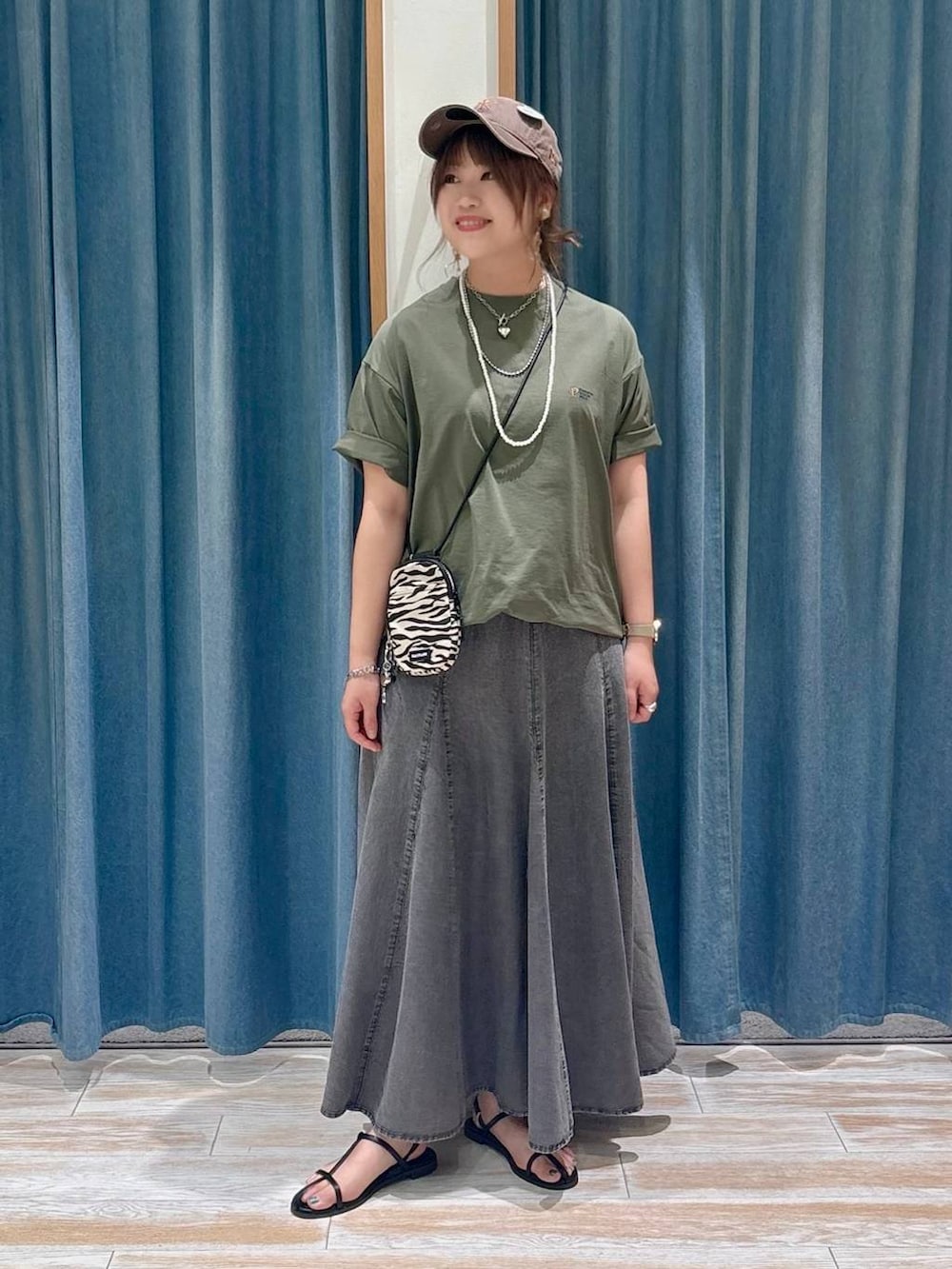 ベージュ系のショルダーバッグ、グリーン系のTシャツ/カットソー、ブラック系のスカートを着用したレディースの春コーディネートの4枚目の写真