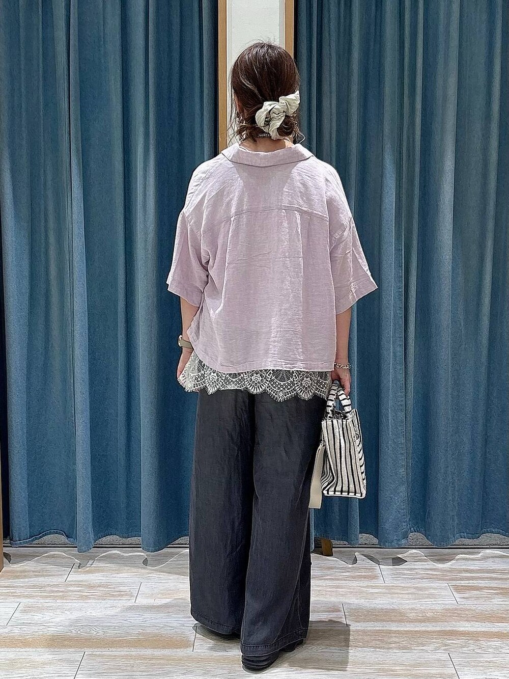 ブラック系のデニムパンツ、ベージュ系のトートバッグ、パープル系のシャツ/ブラウスを着用したレディースの春コーディネートの3枚目の写真