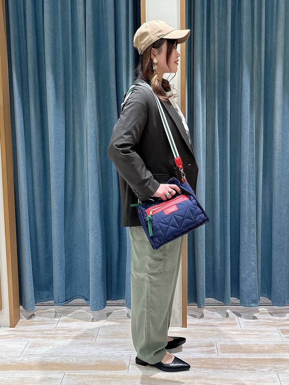 ブルー系のショルダーバッグ、ブラック系のパンプス、グレー系のテーラードジャケットを着用したレディースの春コーディネートの2枚目の写真