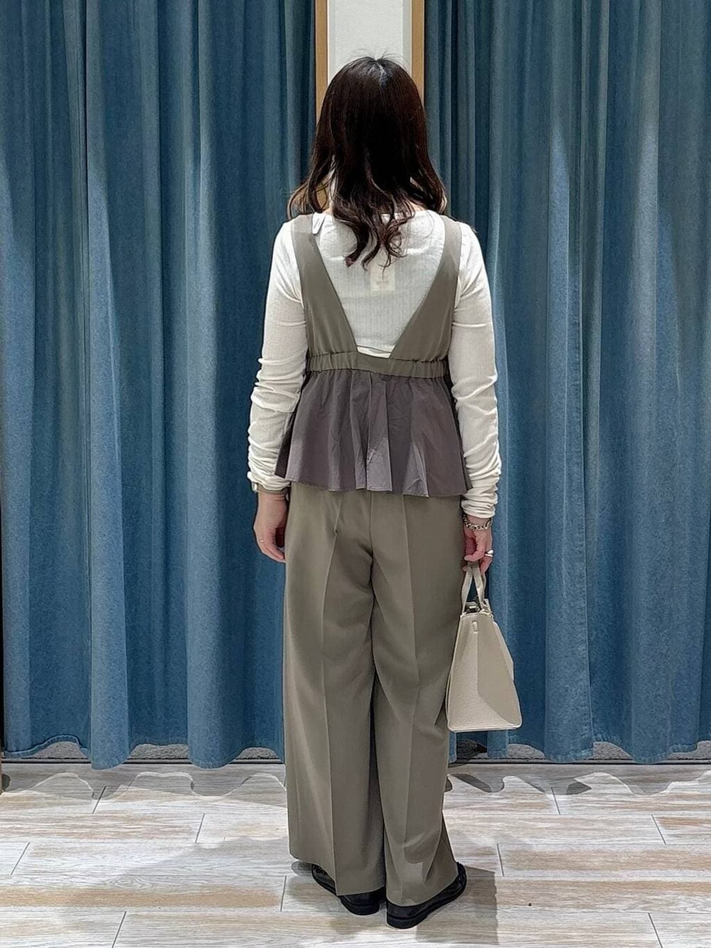 グリーン系のつなぎ/オールインワン、ベージュ系のハンドバッグ、ブラック系のローファーを着用したレディースの冬コーディネートの3枚目の写真