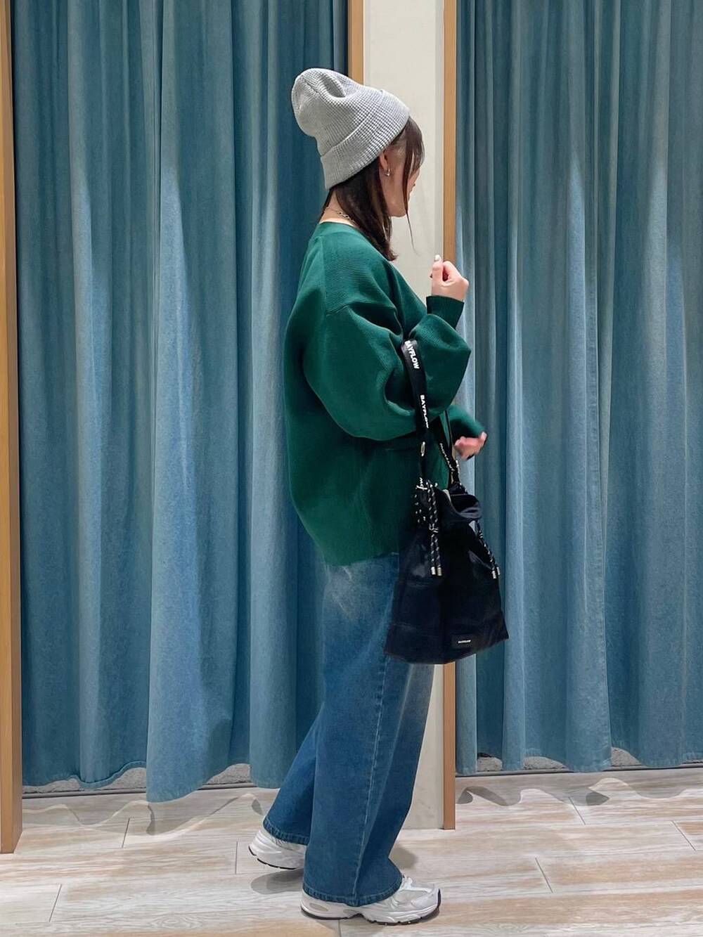 ホワイト系のキャミソール、ブルー系のデニムパンツ、ブラック系のショルダーバッグを着用したレディースの冬コーディネートの2枚目の写真