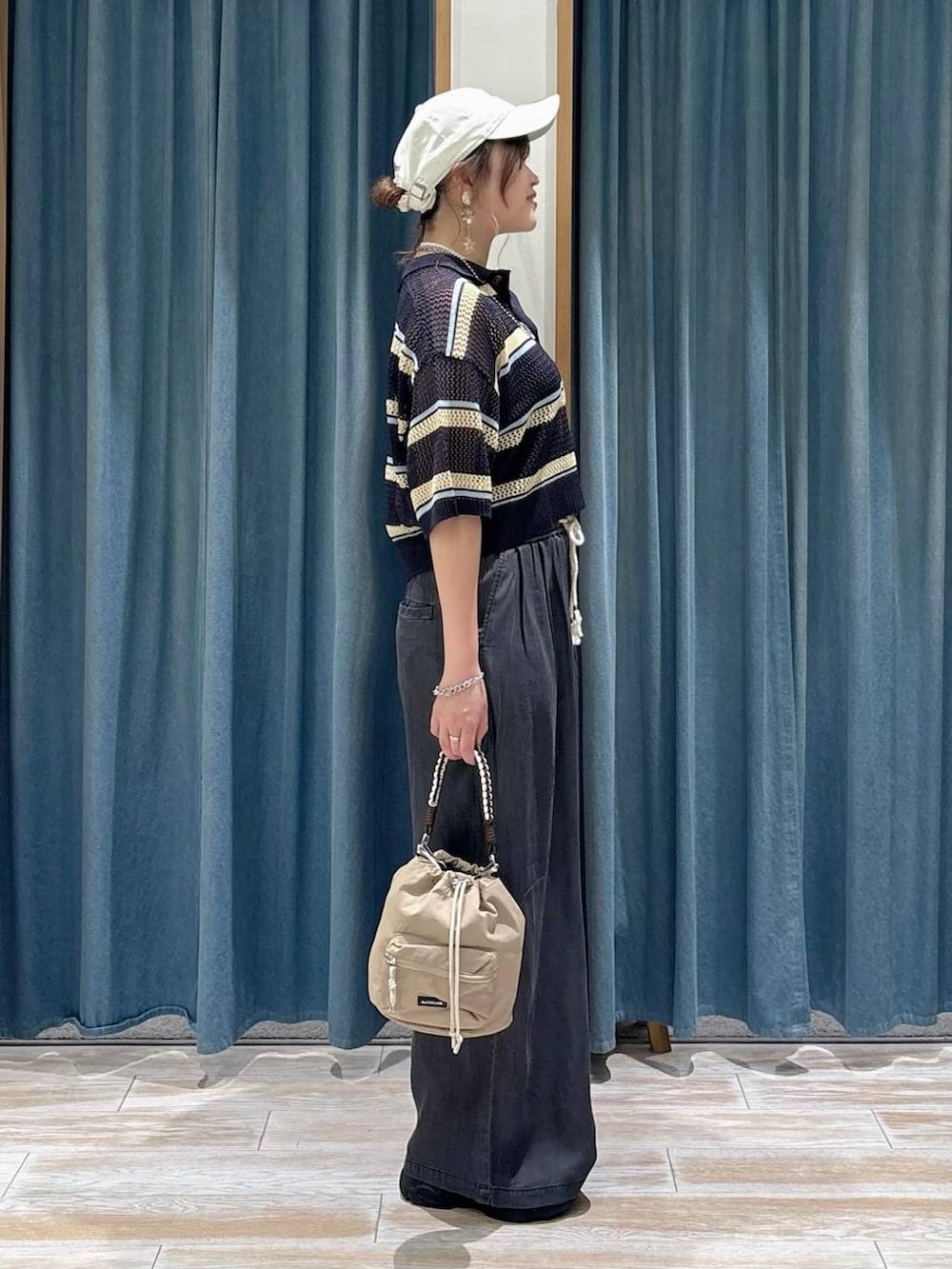 ブラック系のデニムパンツ、ブルー系のポロシャツ、ブラック系のサンダルを着用したレディースの春コーディネートの2枚目の写真