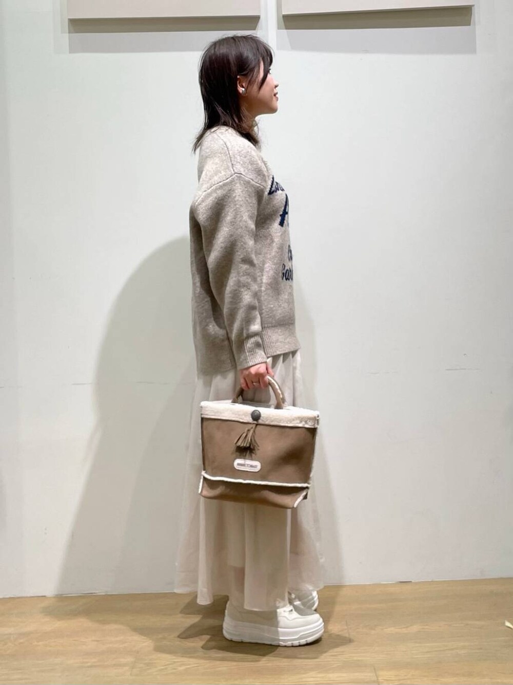 ホワイト系のスニーカー、イエロー系のショルダーバッグ、ベージュ系のニット/セーターを着用したレディースの秋コーディネートの2枚目の写真