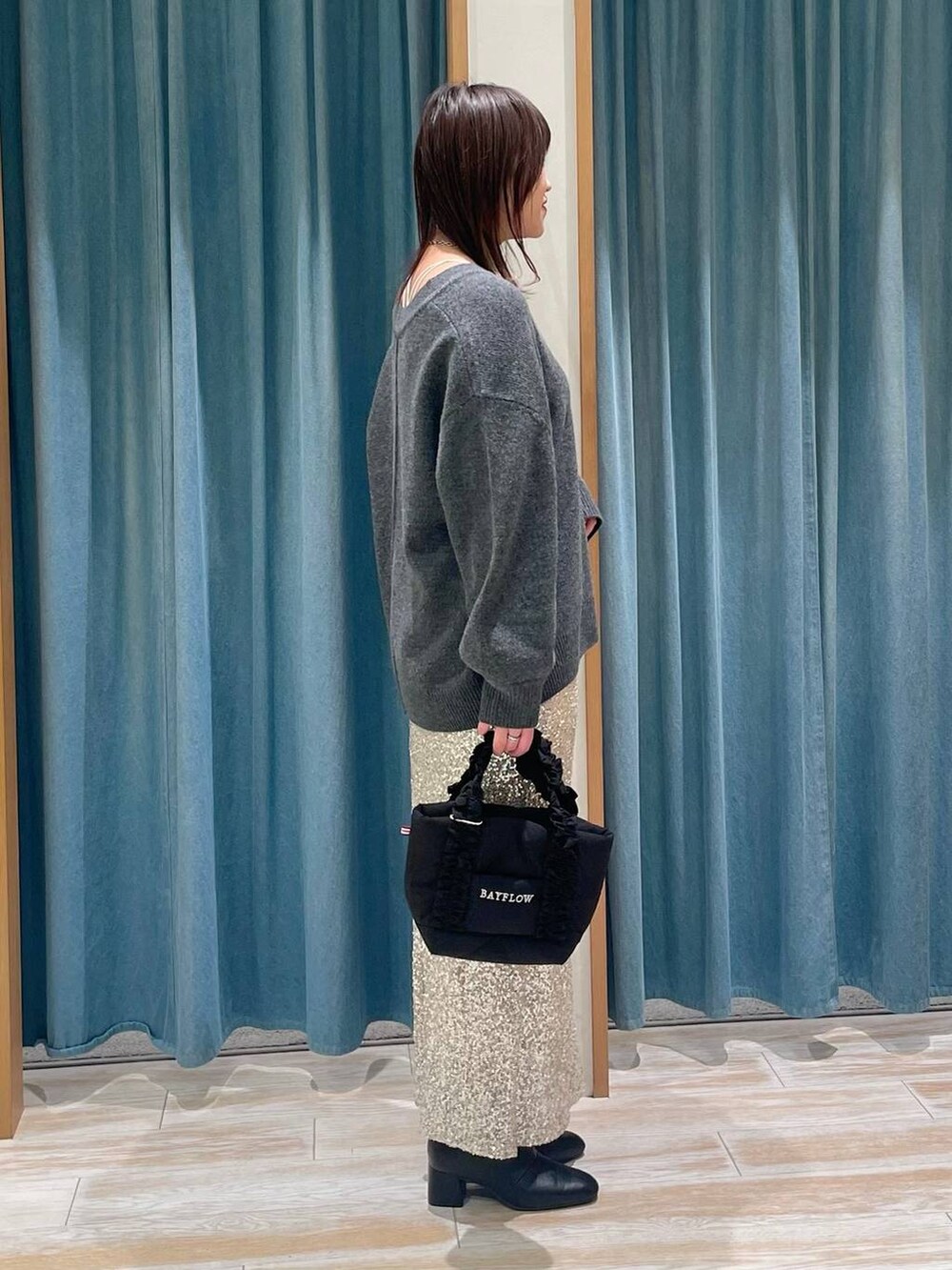 ブラック系のブーツ、グレー系のニット/セーター、ブラック系のトートバッグを着用したレディースの冬コーディネートの2枚目の写真