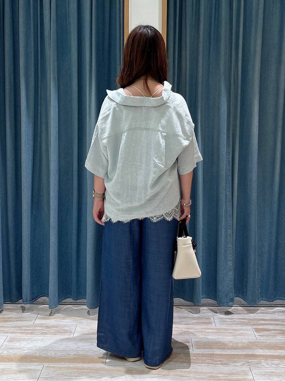 ブルー系のデニムパンツ、シルバー系のサンダル、ホワイト系のキャミソールを着用したレディースの夏コーディネートの3枚目の写真