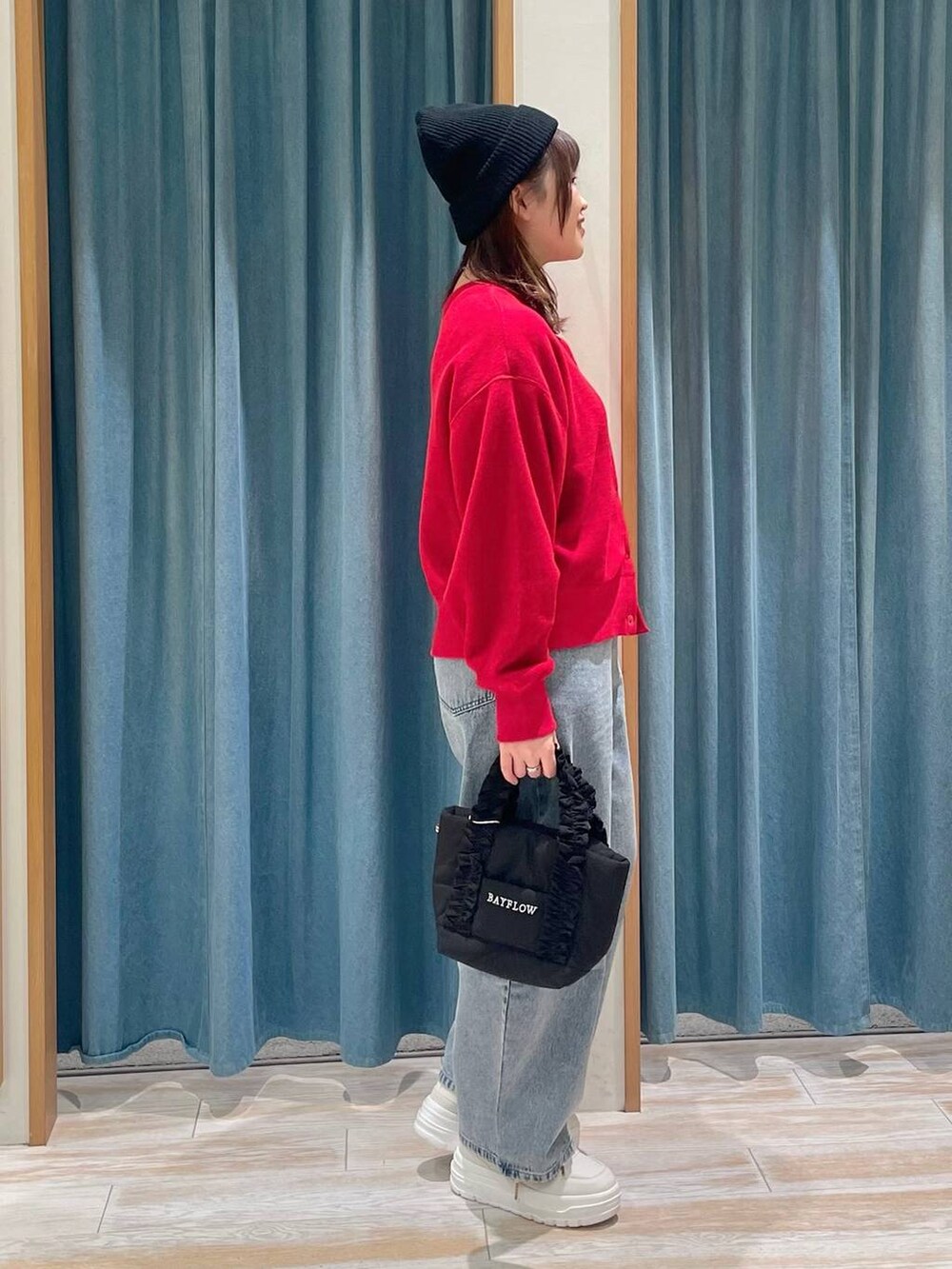 ホワイト系のスニーカー、ブラック系のトートバッグ、ブルー系のデニムパンツを着用したレディースの冬コーディネートの2枚目の写真