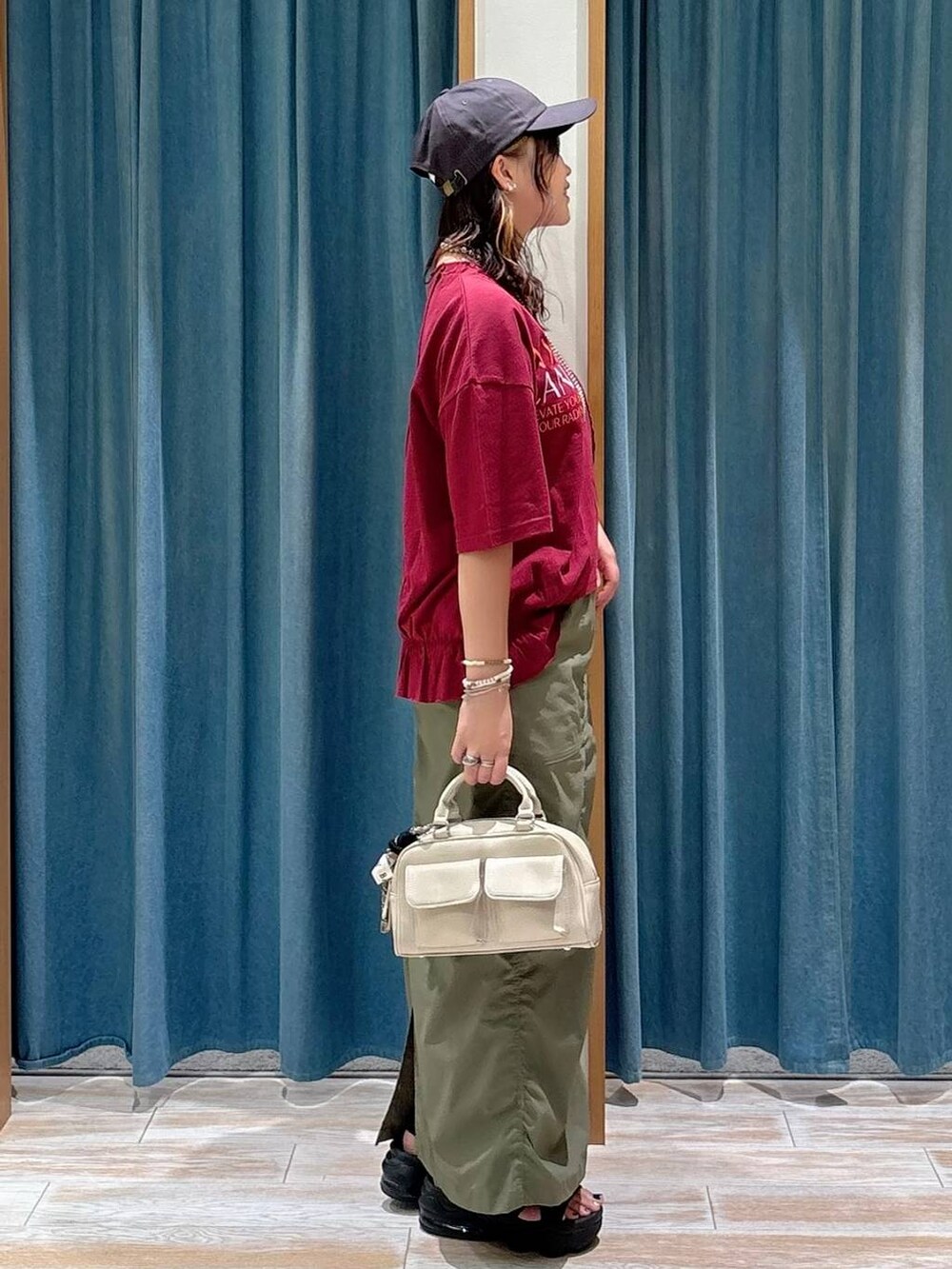 グリーン系のスカート、ホワイト系のボストンバッグ、シルバー系のネックレスを着用したレディースの夏コーディネートの2枚目の写真