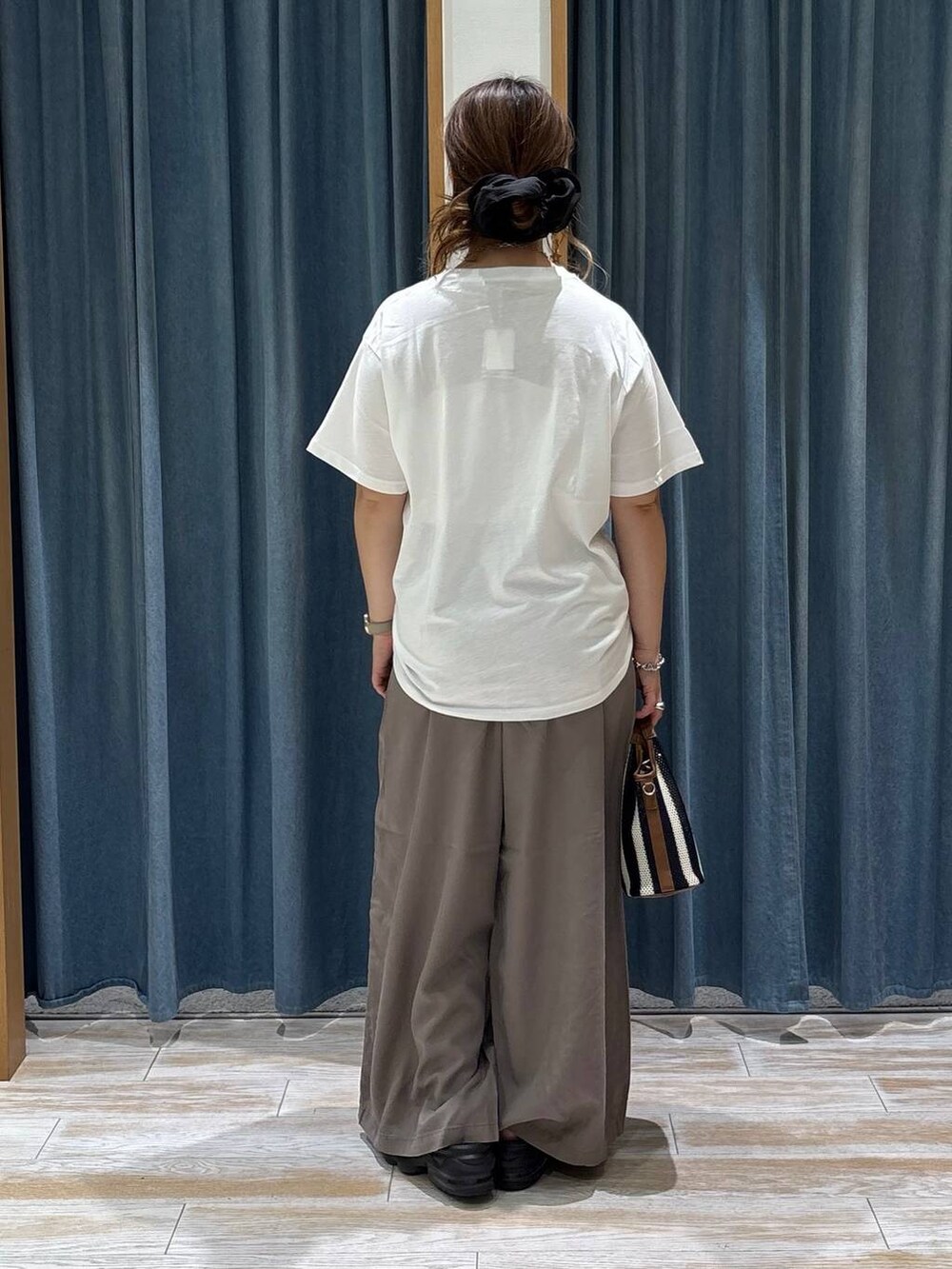 ブラウン系のその他パンツ、ブルー系のショルダーバッグ、ホワイト系のTシャツ/カットソーを着用したレディースの夏コーディネートの3枚目の写真