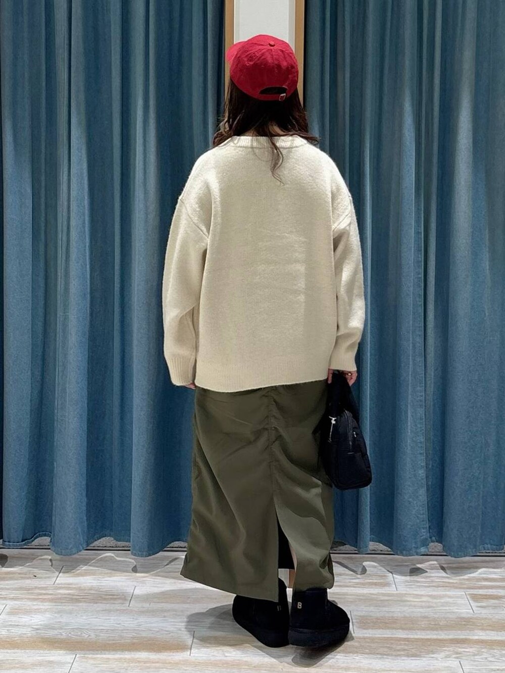 グリーン系のスカート、ブラック系のブーツ、ブラック系のボストンバッグを着用したレディースの秋コーディネートの3枚目の写真