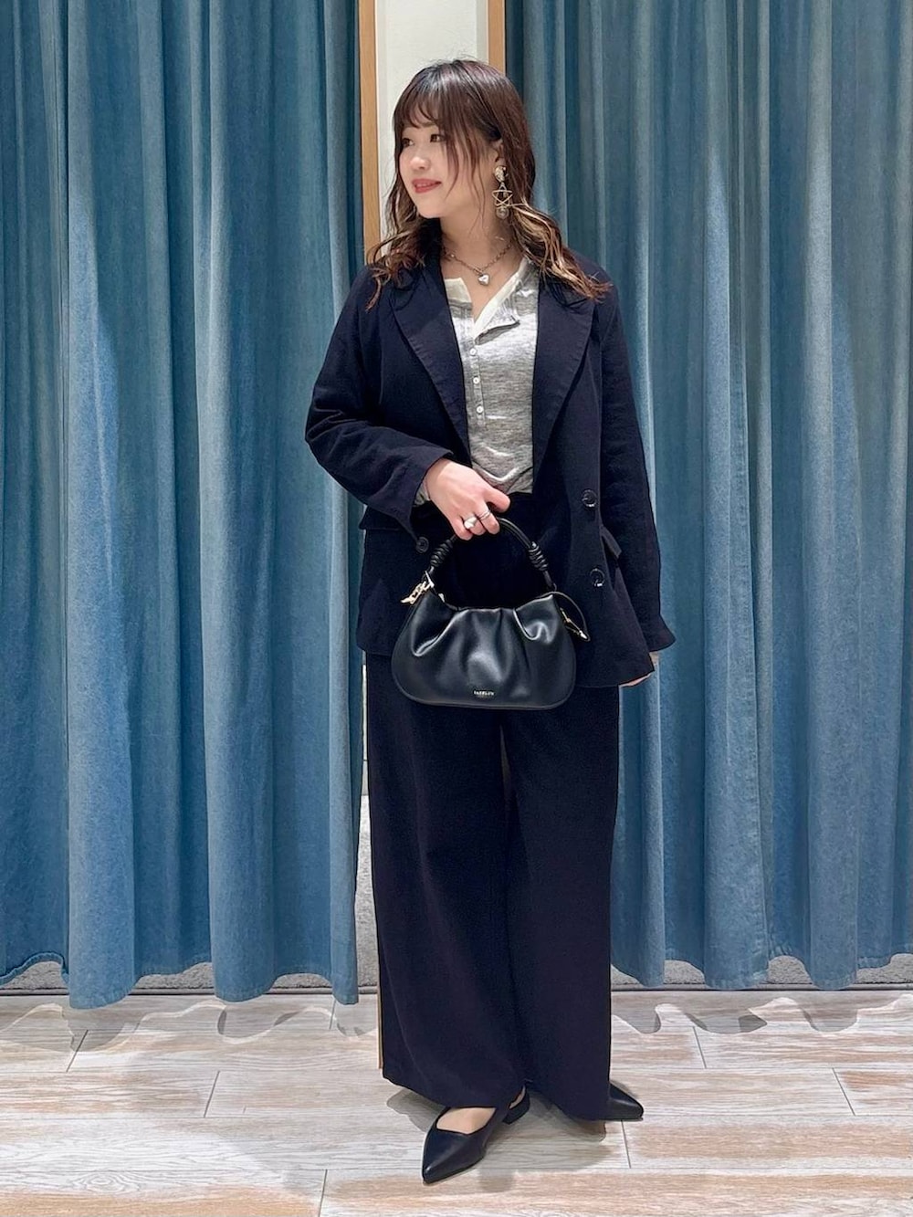 ブラック系のハンドバッグ、ブラック系のパンプス、ブラック系のテーラードジャケットを着用したレディースの春コーディネートの4枚目の写真