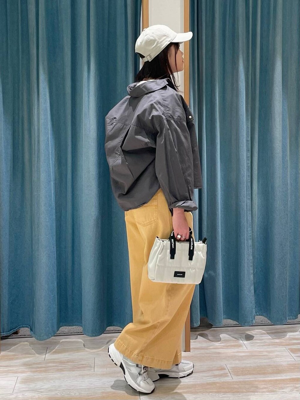 グレー系のシャツ/ブラウス、ベージュ系のショルダーバッグ、ホワイト系のスニーカーを着用したレディースの冬コーディネートの2枚目の写真