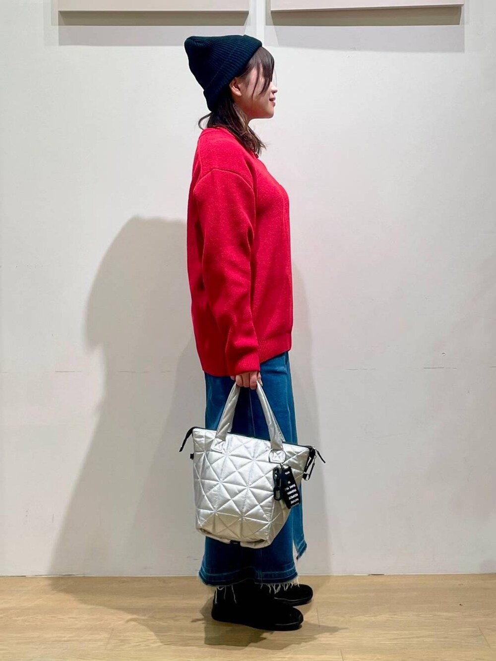 ブルー系のデニムスカート、レッド系のニット/セーター、ブラック系のブーツを着用したレディースの秋コーディネートの3枚目の写真